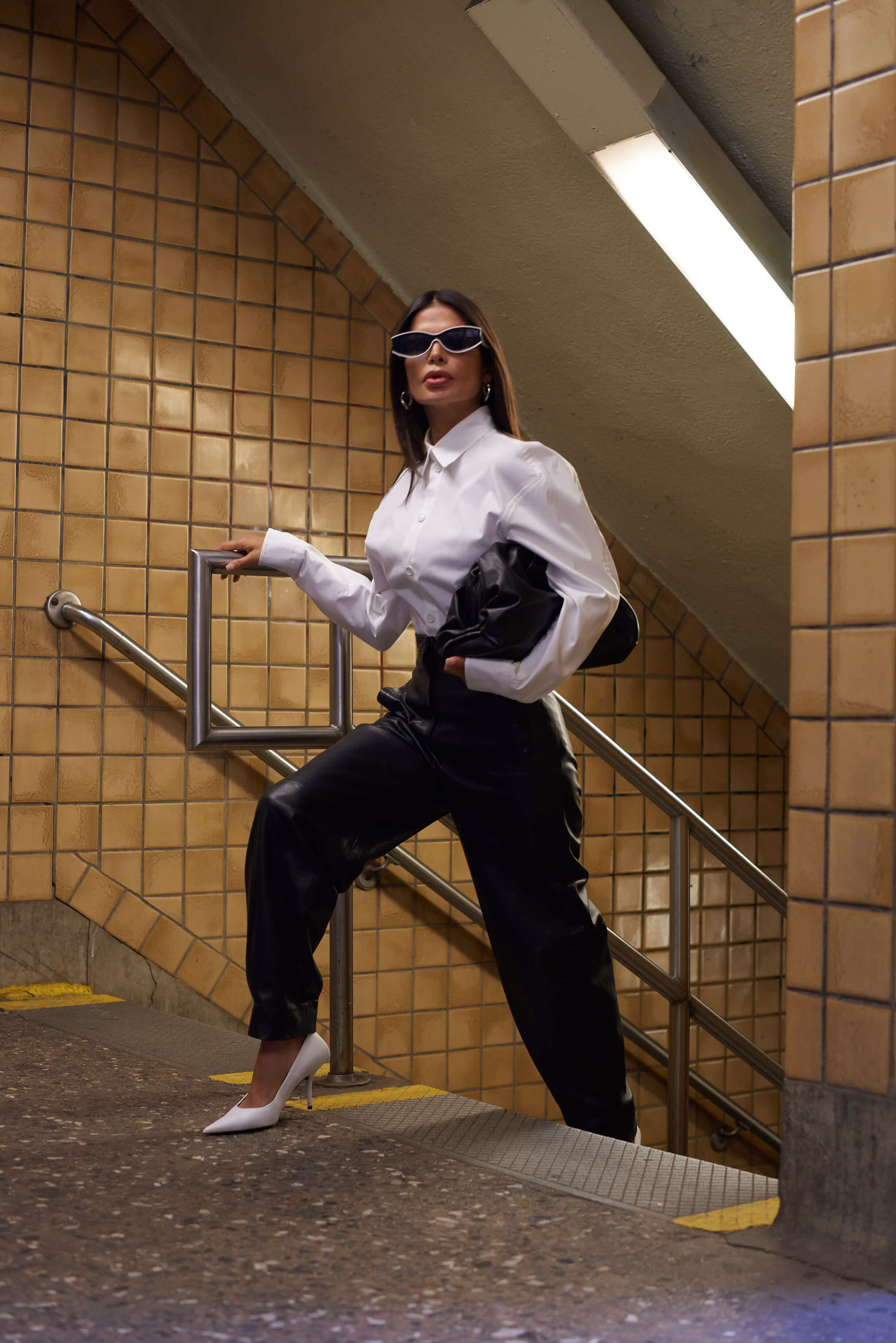 Victoria Barbara street style in New York City subway wearing white Bottega Veneta blouse top, Khaite black pants, black Bottega Veneta pouch handbag, white Balenciaga heeled shoes, & Loewe sunglasses during New York Fashion Week 2021