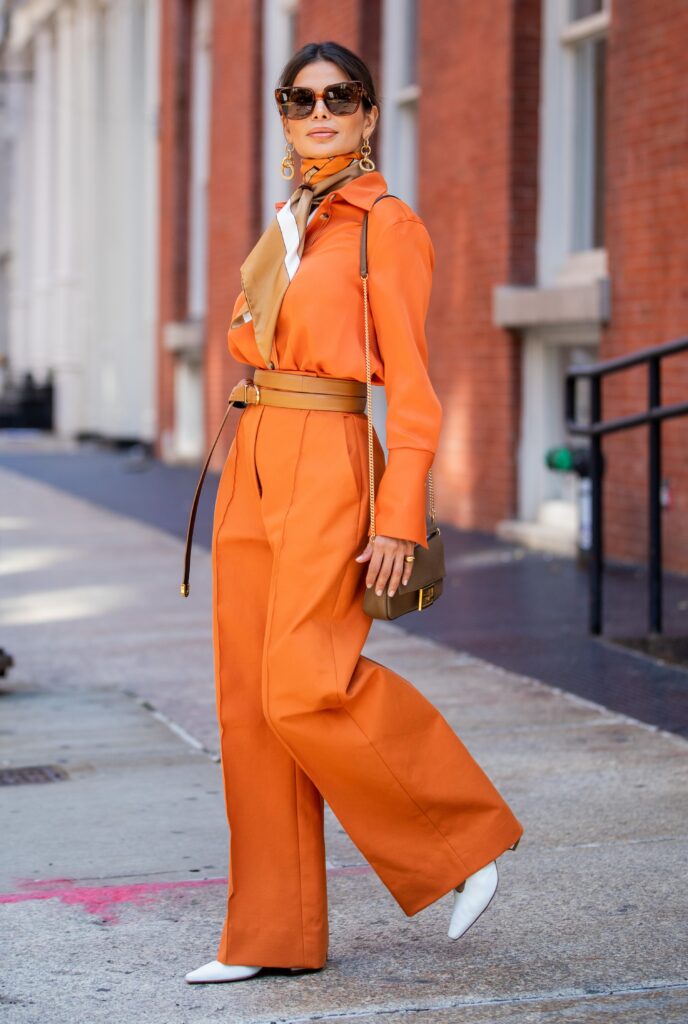 Victoria Barbara walking in New York City wearing a KHAITE shirt and trousers styled with a Burberry scarf and Bottega Veneta shoes.