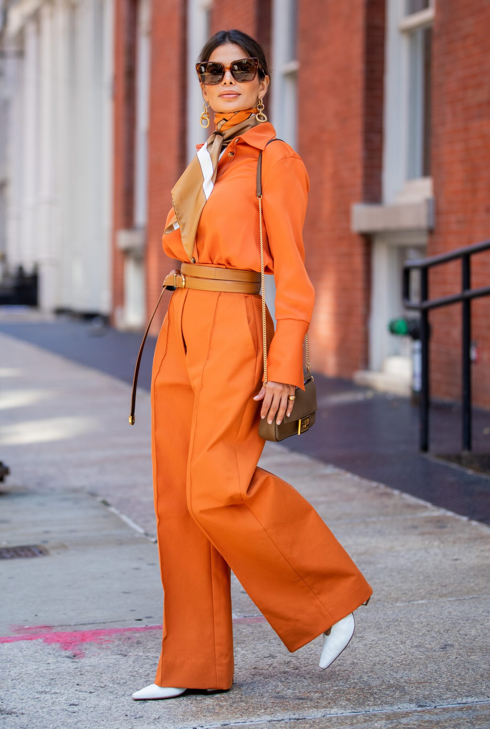 Victoria Barbara walking in New York City wearing a KHAITE shirt and trousers styled with a Burberry scarf and Bottega Veneta shoes.