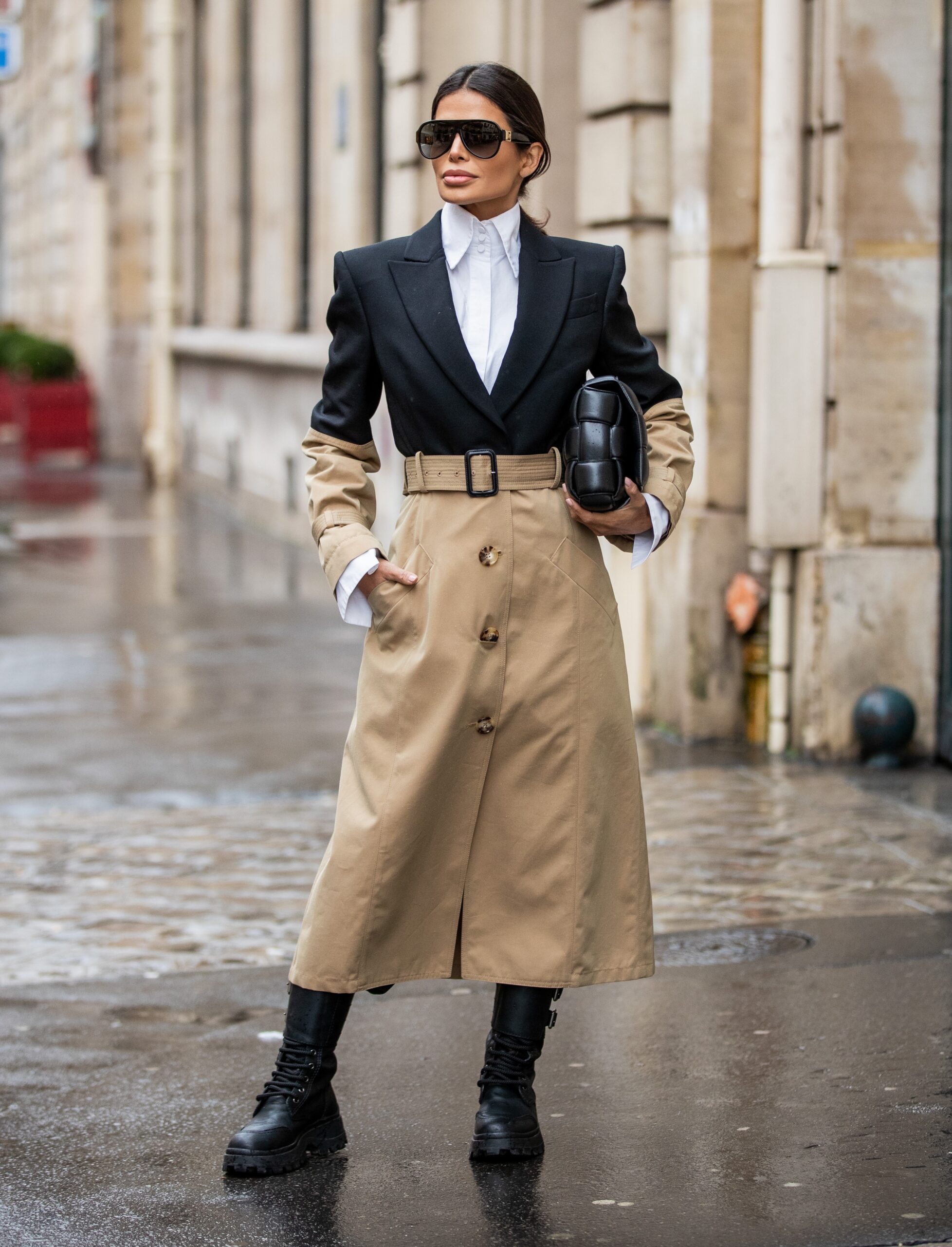 Full-length street style portrait of Victoria Barbara in a structured two-tone trench coat with combat boots and oversized sunglasses during Paris Fashion Week.