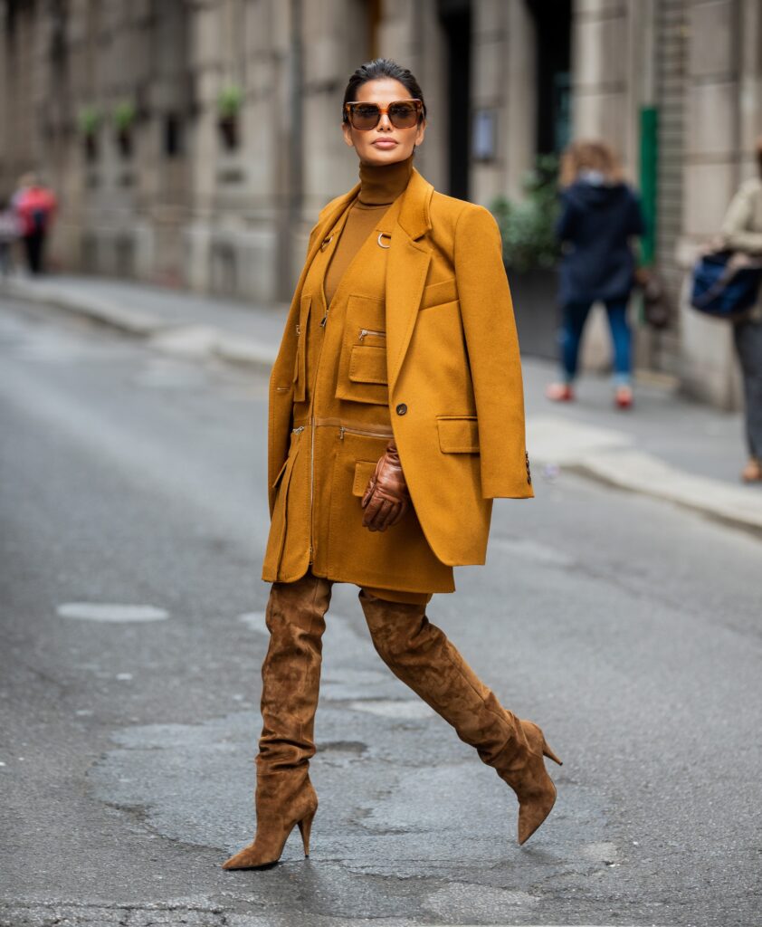 Victoria Barbara walking through Milan during Milan Fashion Week wearing a monochromatic Max Mara ensemble with Saint Laurent suede boots and Celine sunglasses.