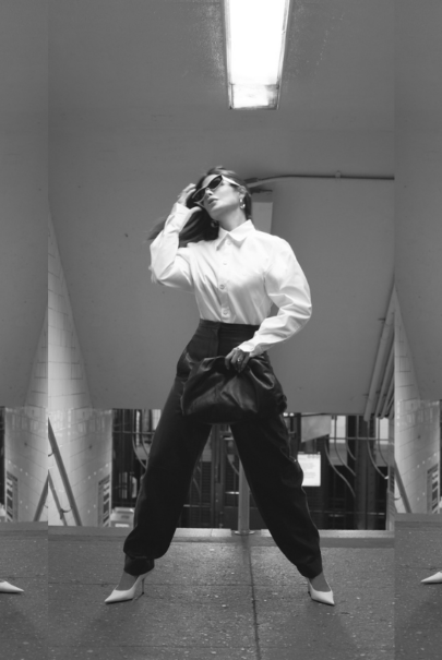 Victoria Barbara street style in New York City subway wearing white Bottega Veneta blouse top, Khaite black pants, black Bottega Veneta pouch handbag, white Balenciaga heeled shoes, & Loewe sunglasses during New York Fashion Week 2021