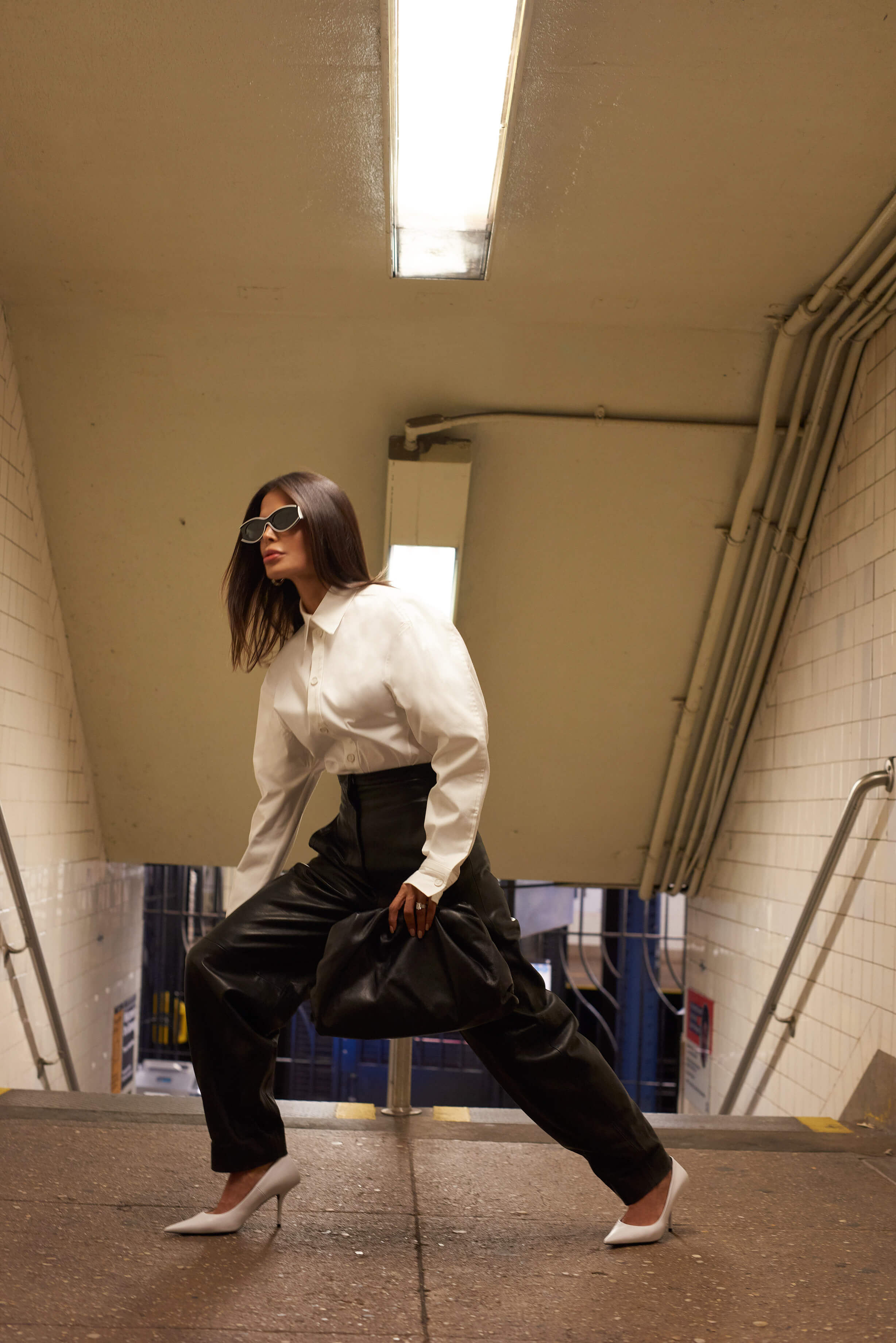 Victoria Barbara street style in New York City subway wearing white Bottega Veneta blouse top, Khaite black pants, black Bottega Veneta pouch handbag, white Balenciaga heeled shoes, & Loewe sunglasses during New York Fashion Week 2021