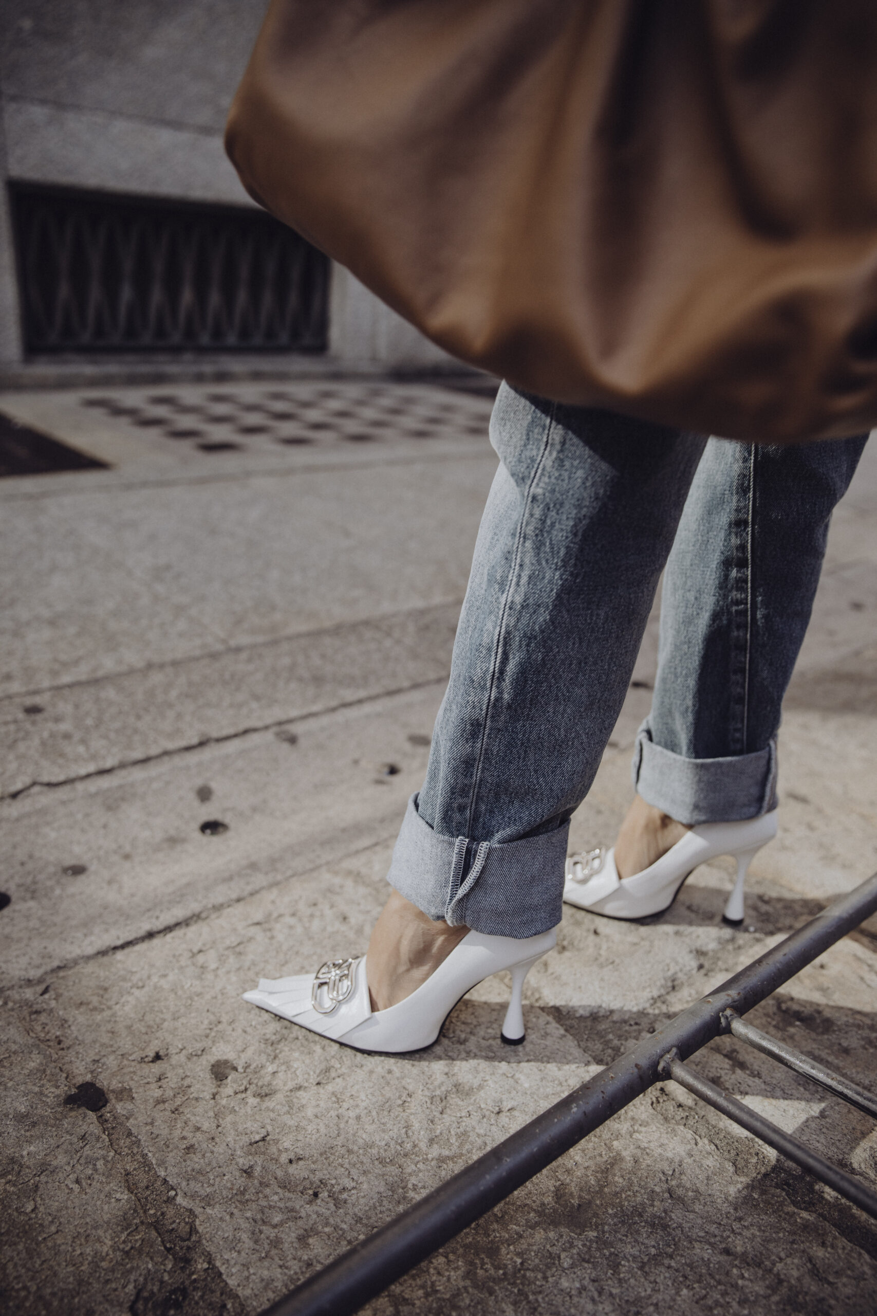 Close-up of white heels styled with denim and Balenciaga blazer