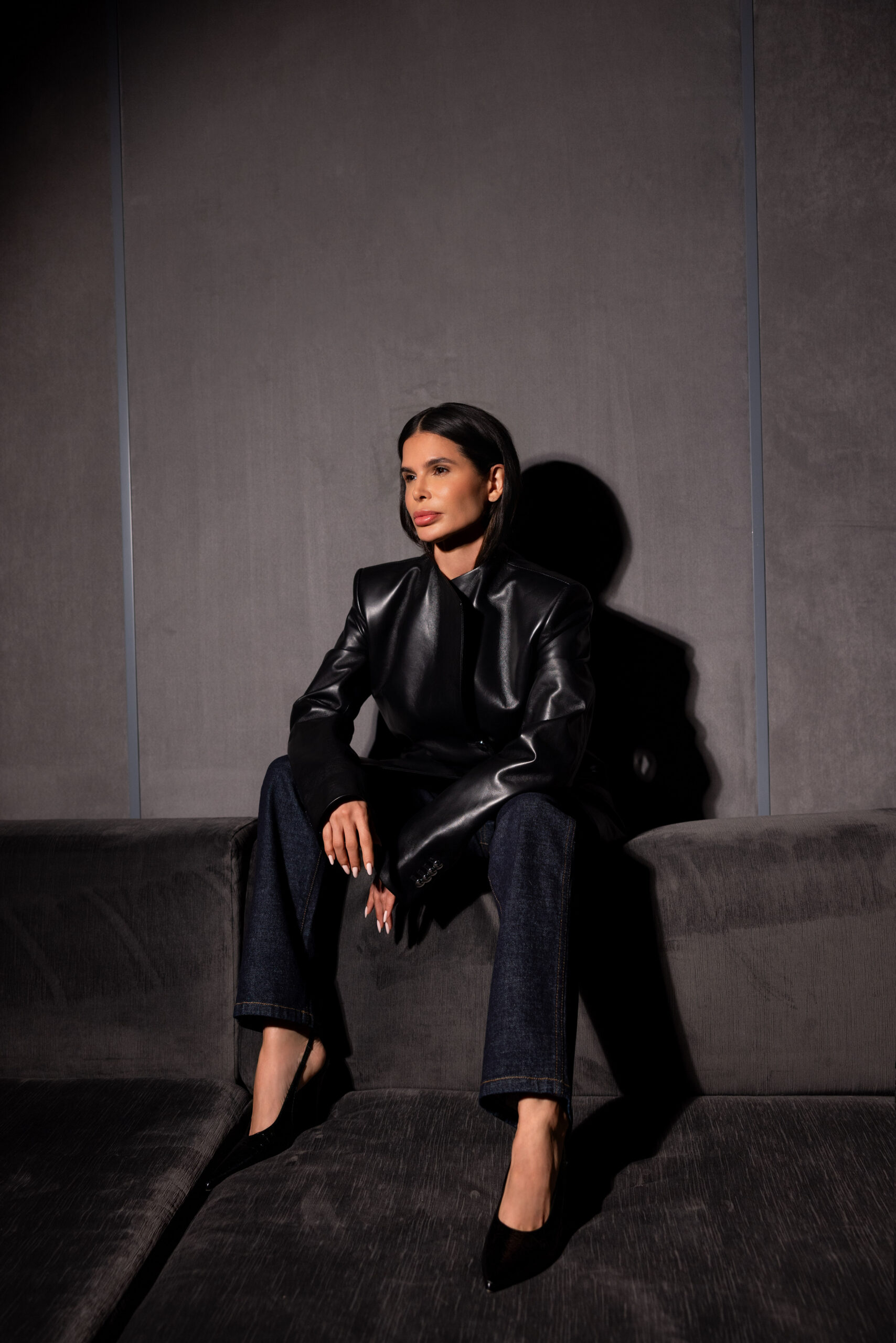Victoria Barbara in Khaite black leather jacket and tailored trousers seated in sculptural studio environment

