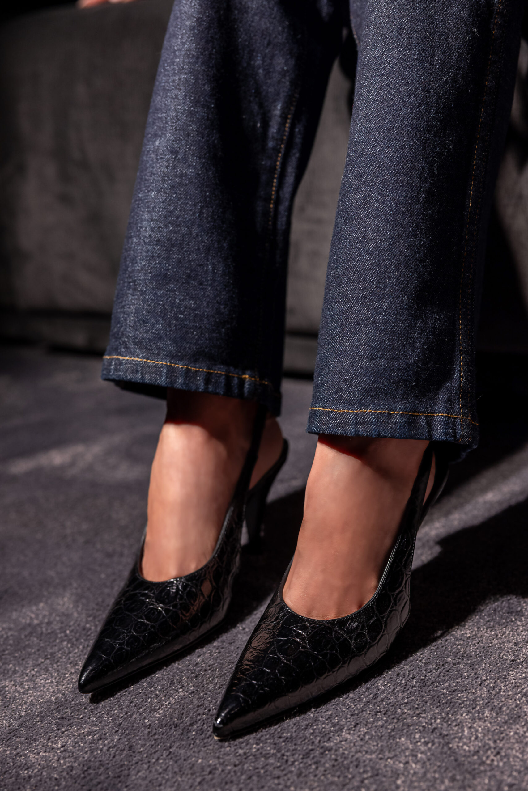 Victoria Barbara wearing Khaite black pointed heels with tailored denim trousers in editorial detail shot