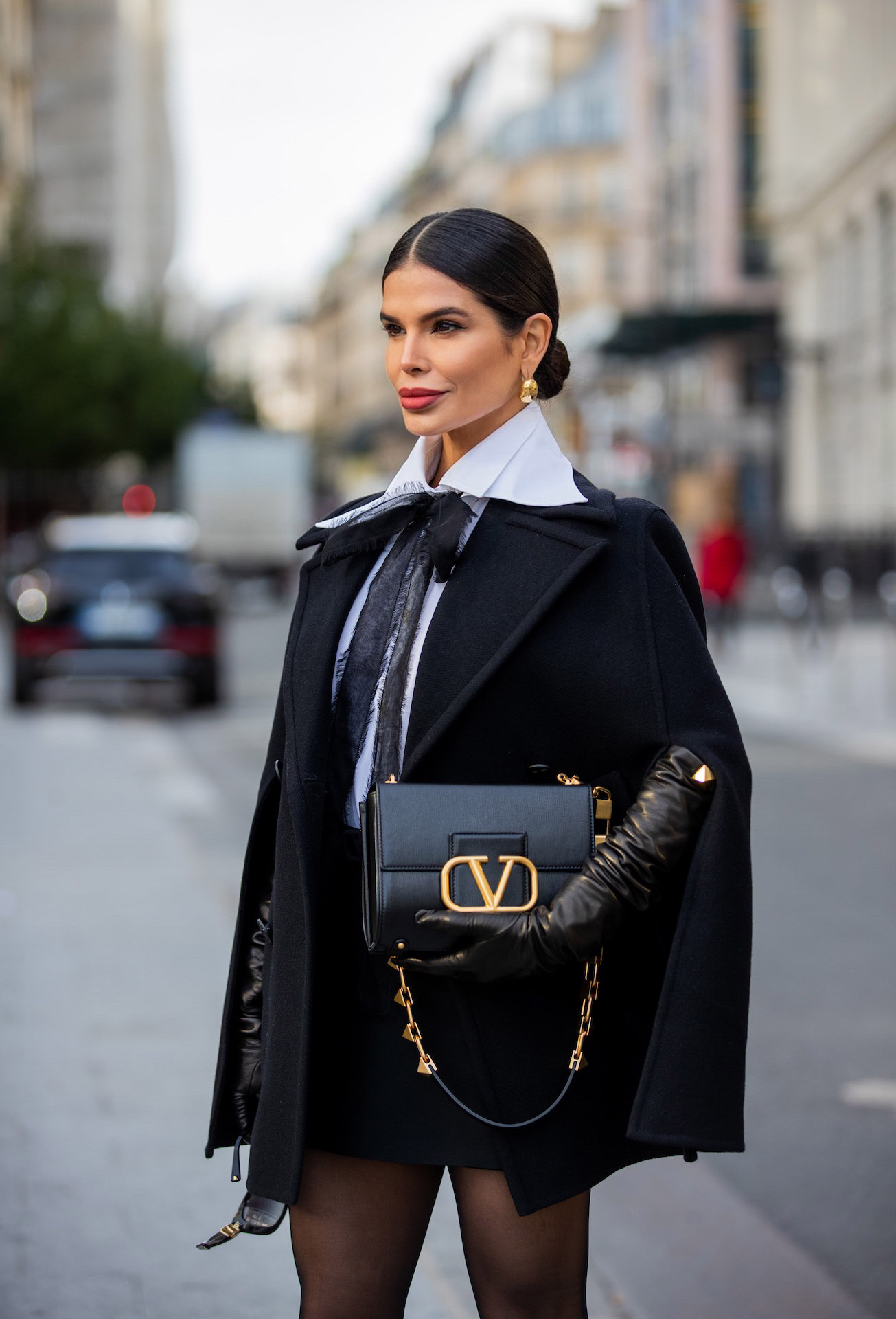 Valentino VLogo black handbag with gold chain detail styled with black gloves Paris Fashion Week