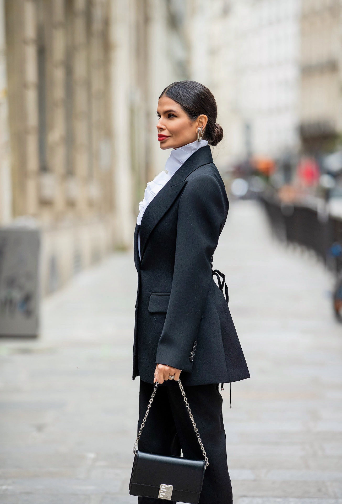Side profile of Victoria Barbara in structured black Alexander McQueen blazer and trousers Paris