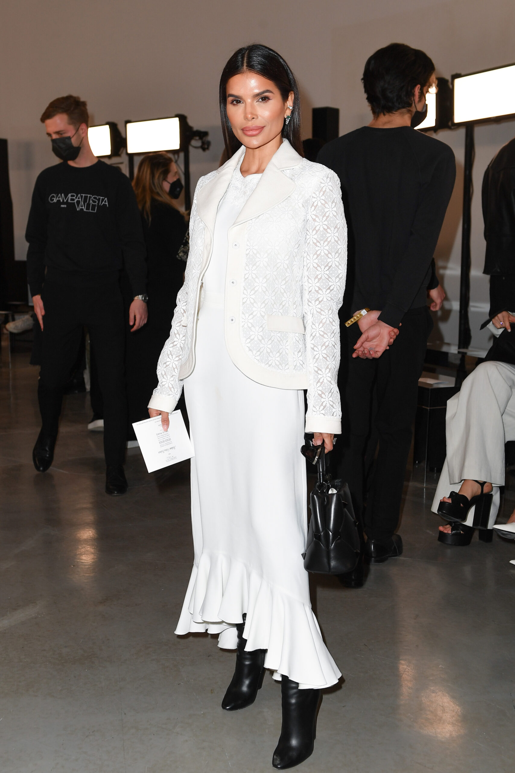 Victoria Barbara inside Giambattista Valli show wearing a white dress and lace jacket with black boots and handbag Paris Fashion Week