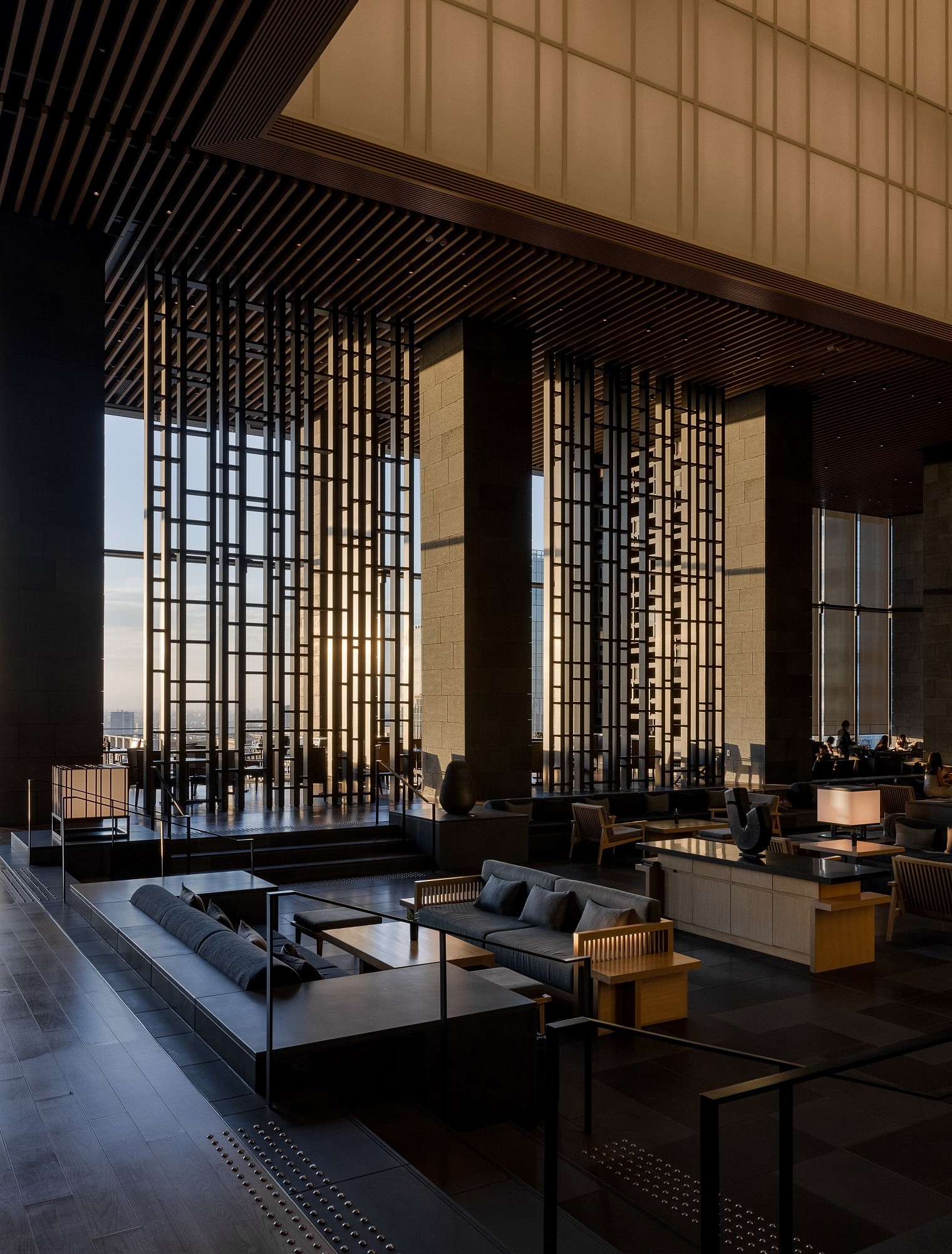 Aman Tokyo lounge interior with dark architectural lines, low seating, and warm ambient lighting