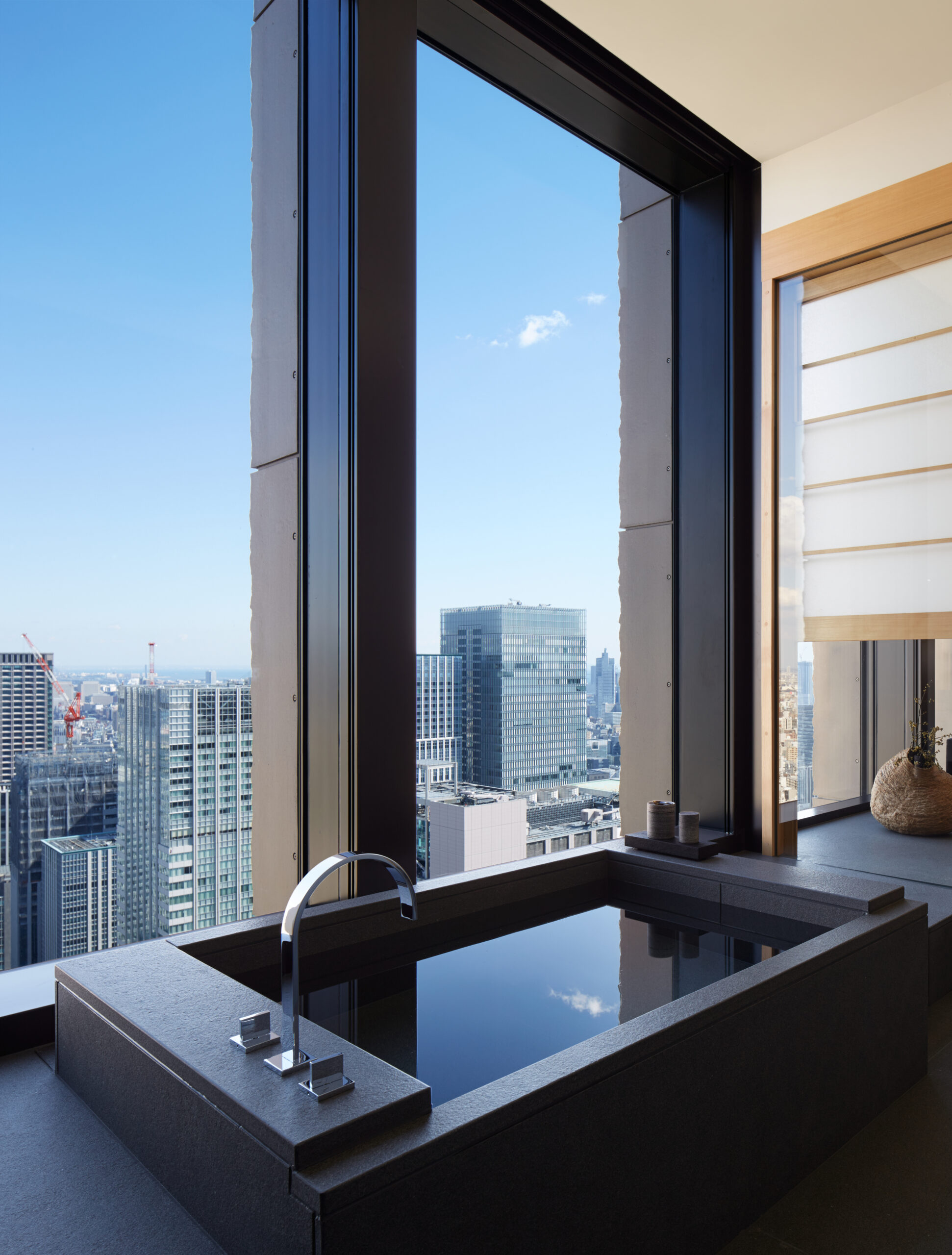 Aman Tokyo suite bathroom with black soaking tub and floor-to-ceiling window overlooking Tokyo skyline