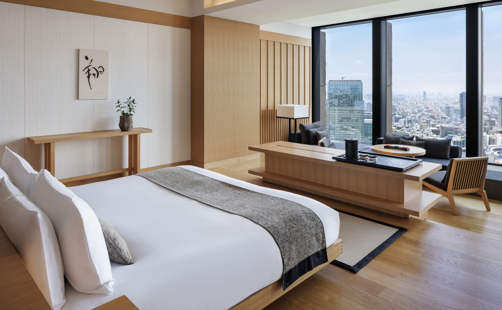 Aman Tokyo bedroom with minimalist design, wooden details, and panoramic city views through large windows