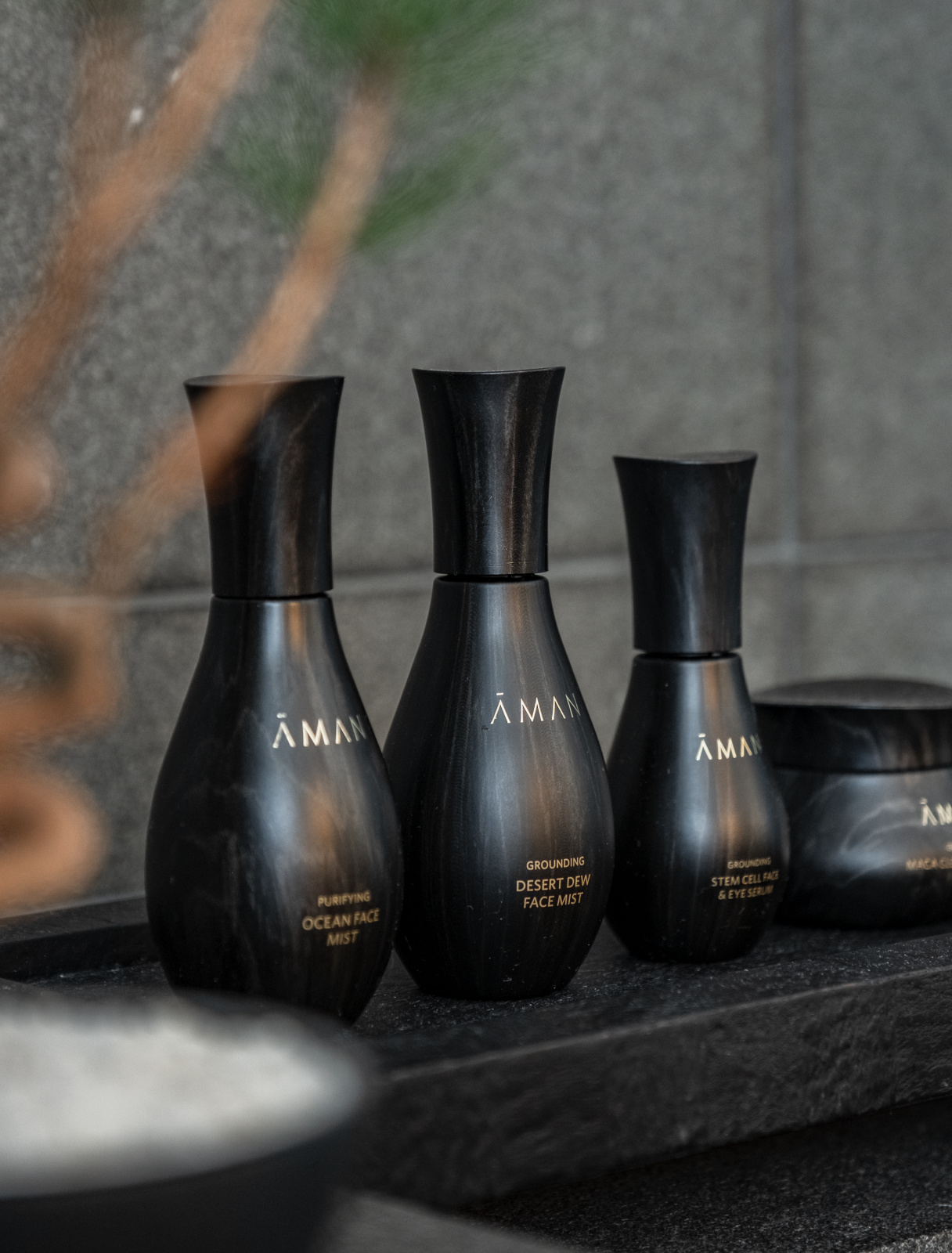 Aman Tokyo skincare products displayed on a dark surface with minimal lighting and clean composition