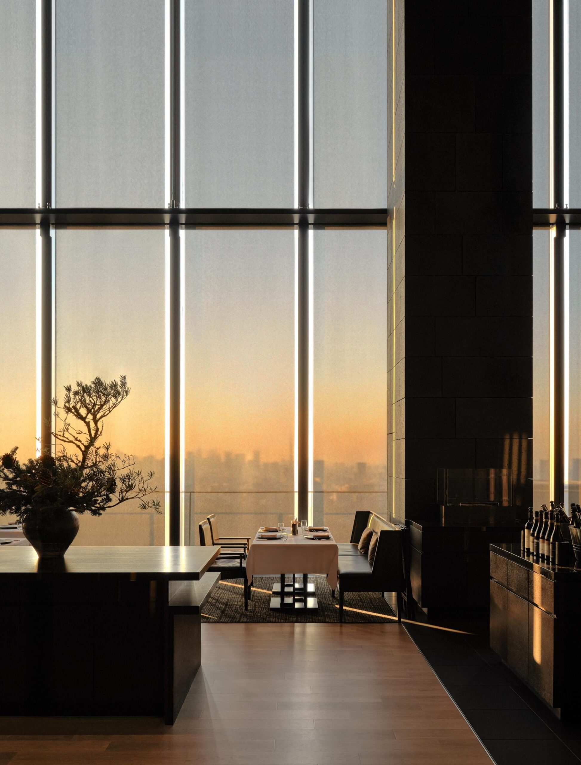 Aman Tokyo interior with floor-to-ceiling windows overlooking Tokyo at sunset with warm light filling the space