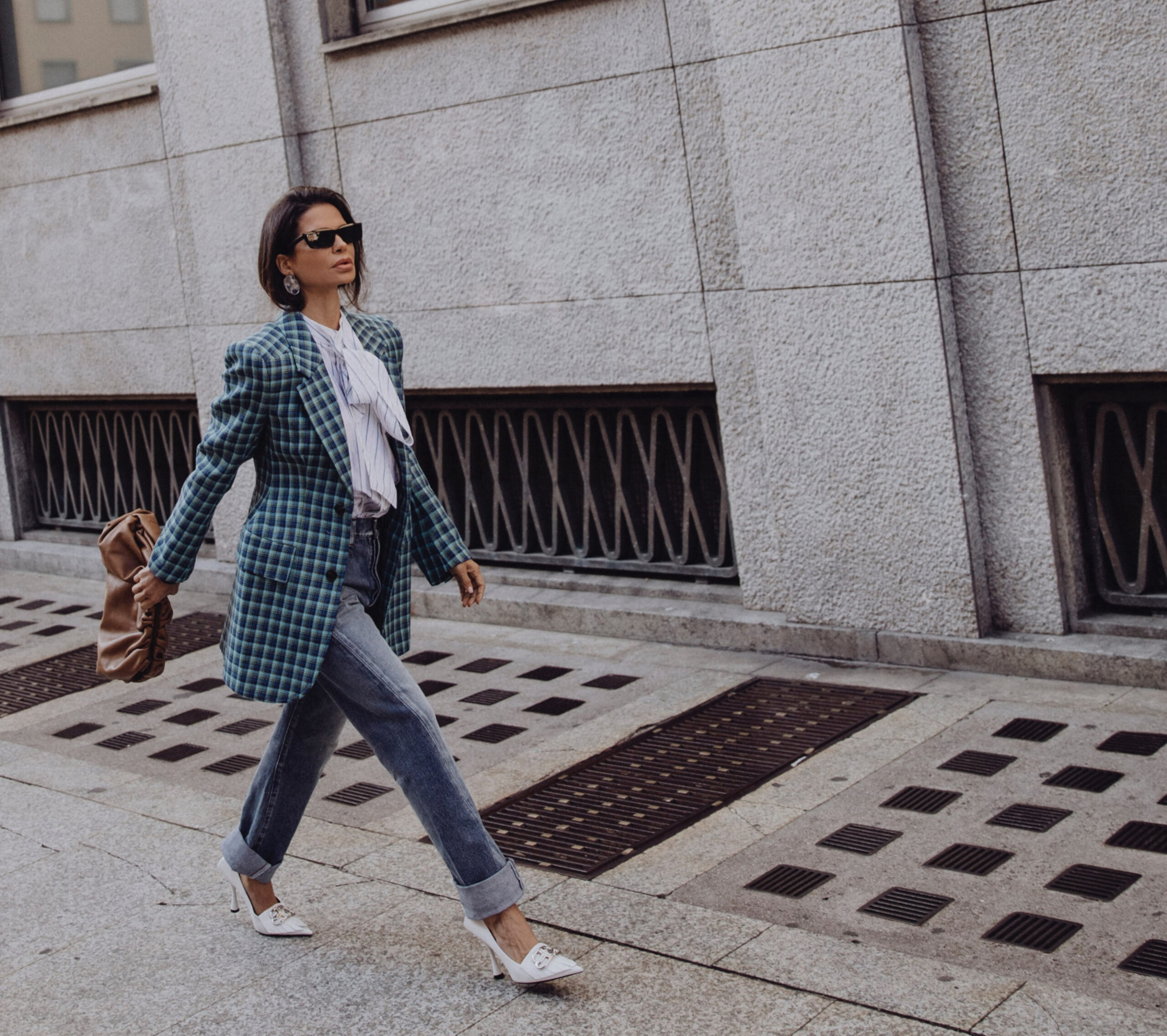 Woman wearing Balenciaga blazer with denim and heels walking in a city street