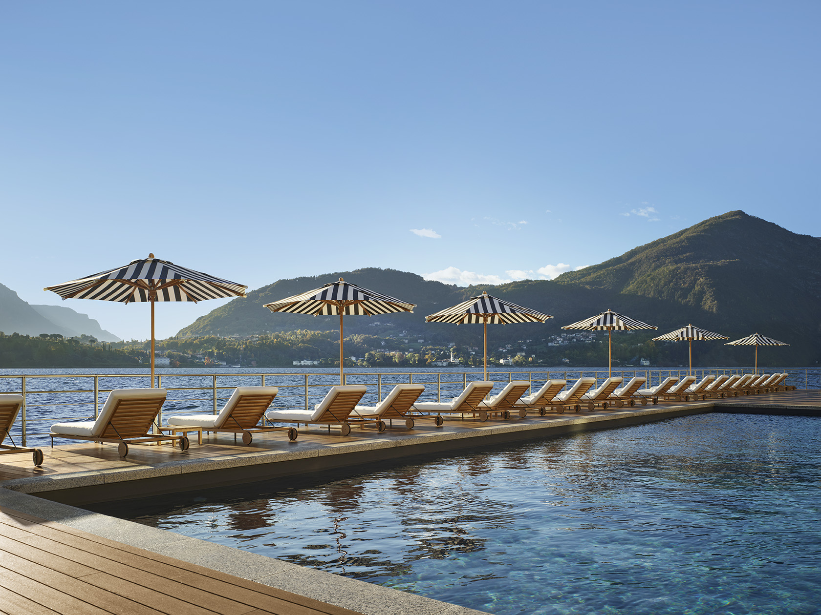 The Lake Como EDITION pool deck overlooking Lake Como with mountains and loungers