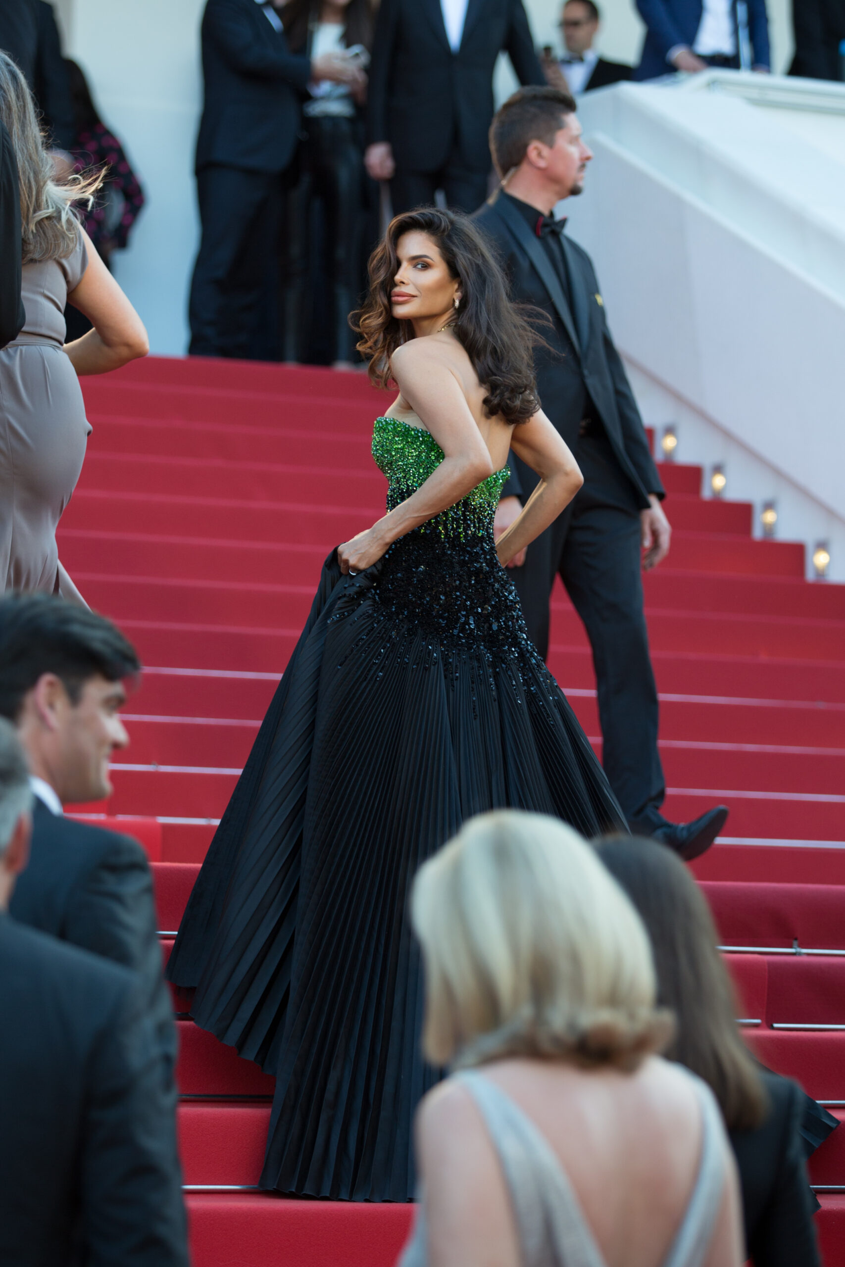 Victoria Barbara walking up the Cannes Film Festival red carpet stairs wearing a strapless green to black Tony Ward Couture gown and Bvlgari necklace