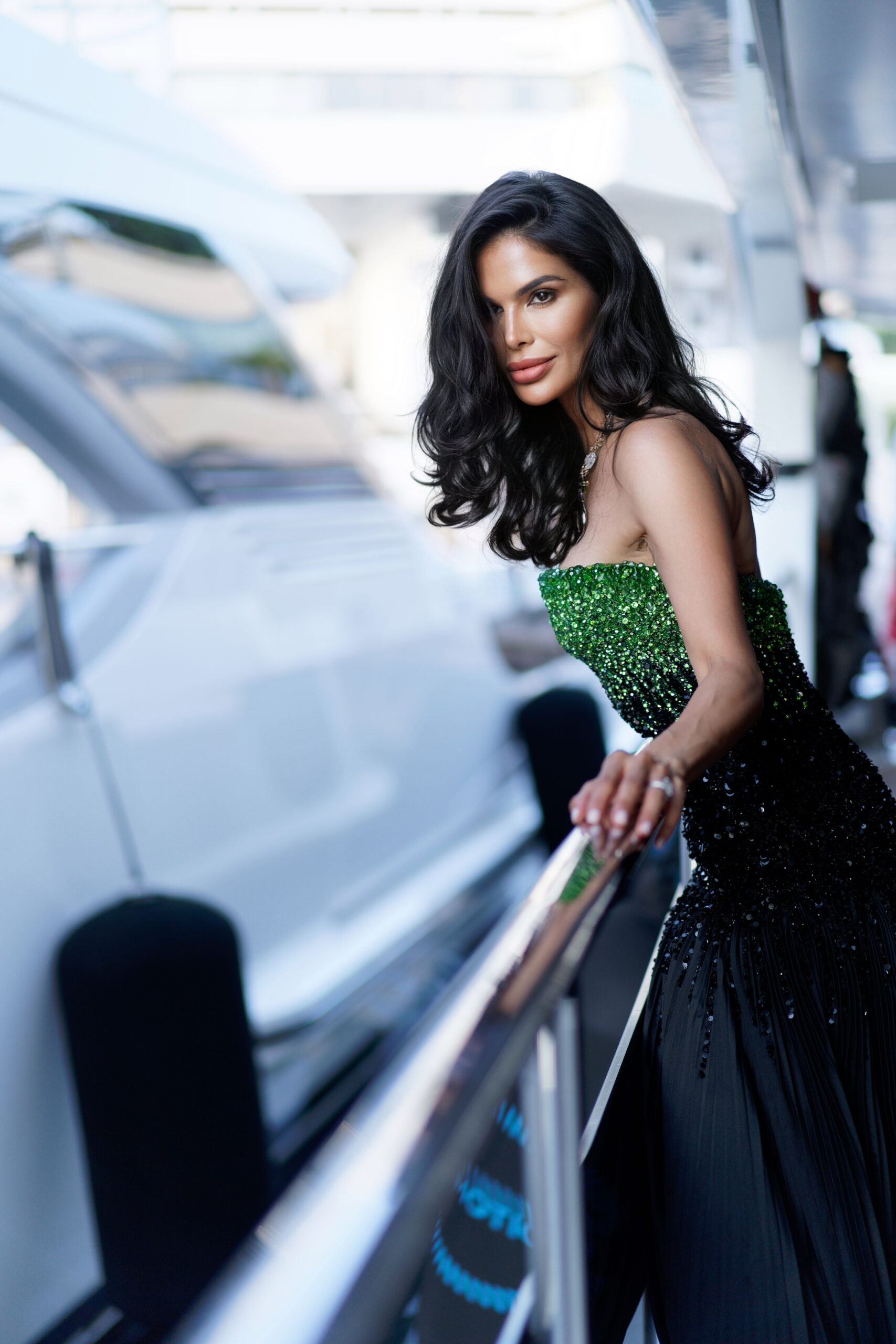 Victoria Barbara leaning on a yacht railing in Cannes wearing Tony Ward Couture gown with green beaded bodice and black skirt