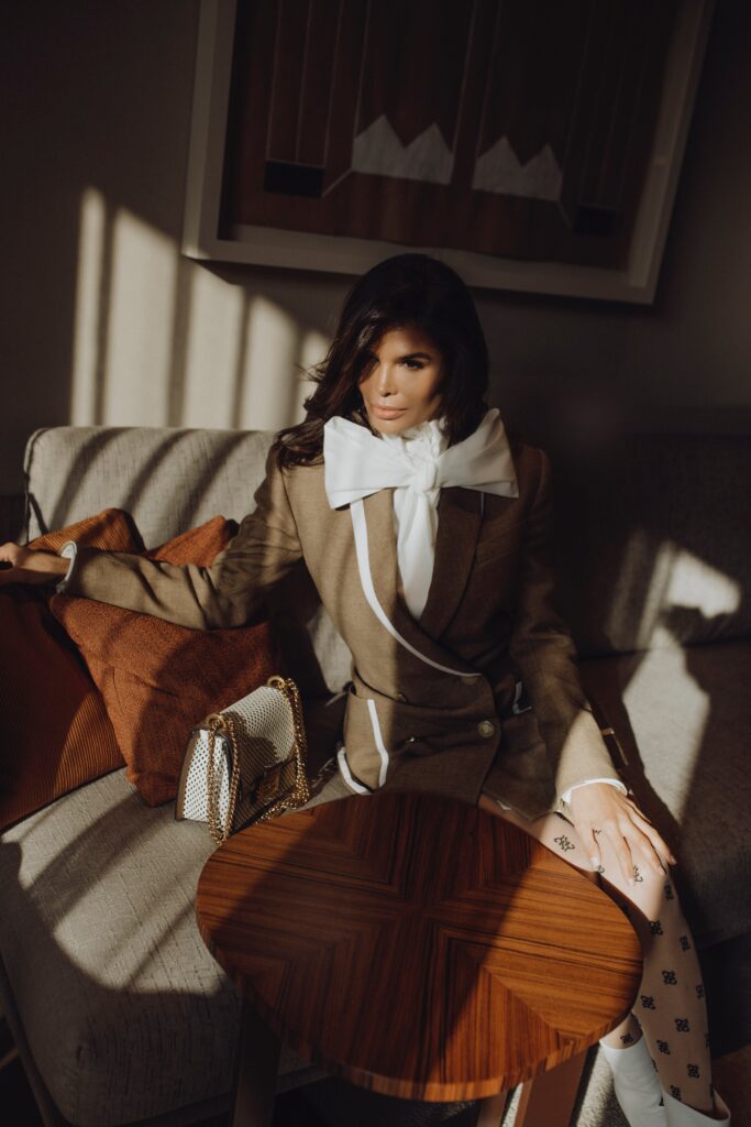 Fendi tailored blazer and bow blouse styled in warm natural light, seated editorial composition with structured silhouette.