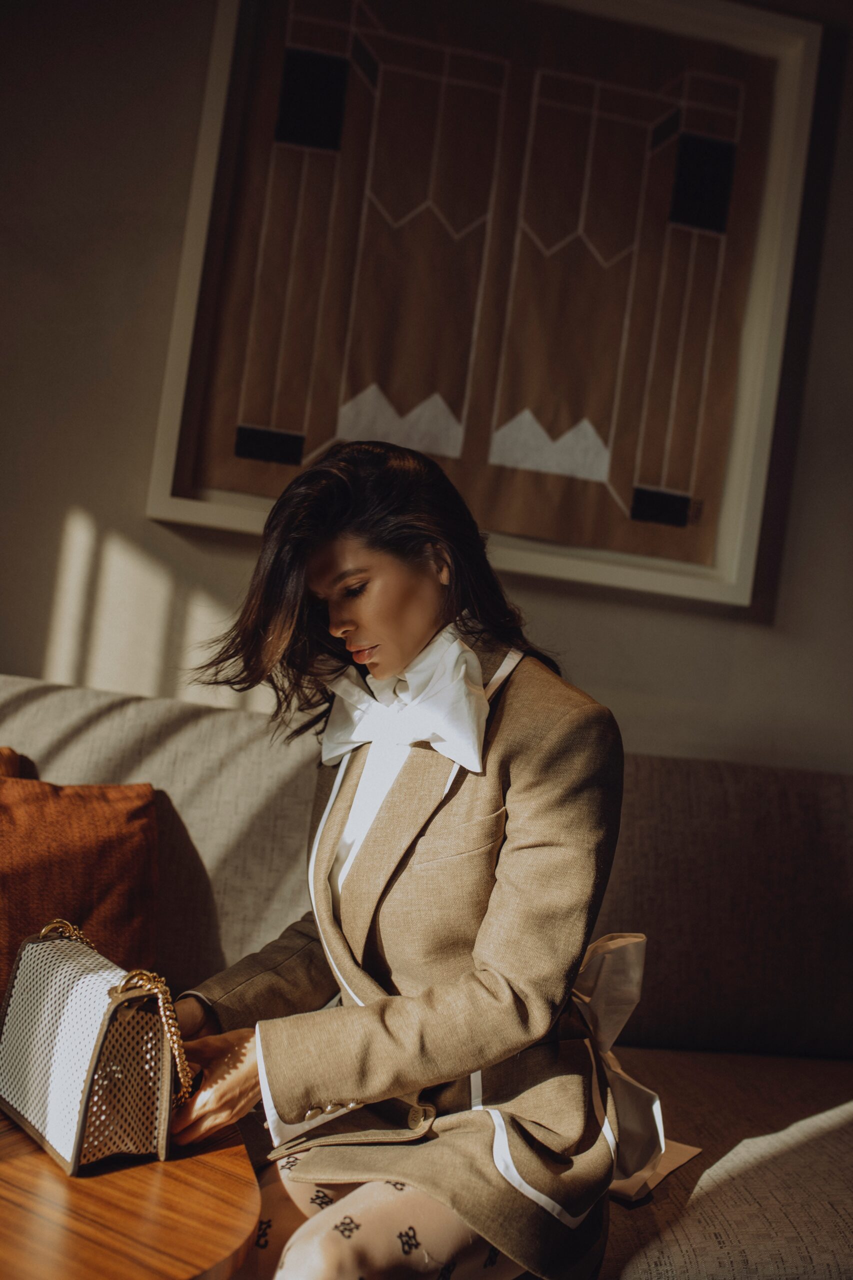 Side profile wearing Fendi full look with structured blazer and statement blouse, styled with Fendi bag in soft interior light.