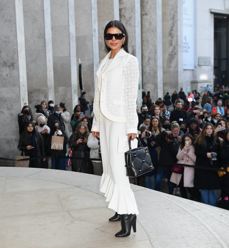 Victoria Barbara arriving at a Paris Couture Week show outside a venue, wearing a white tailored look, photographed among a crowd