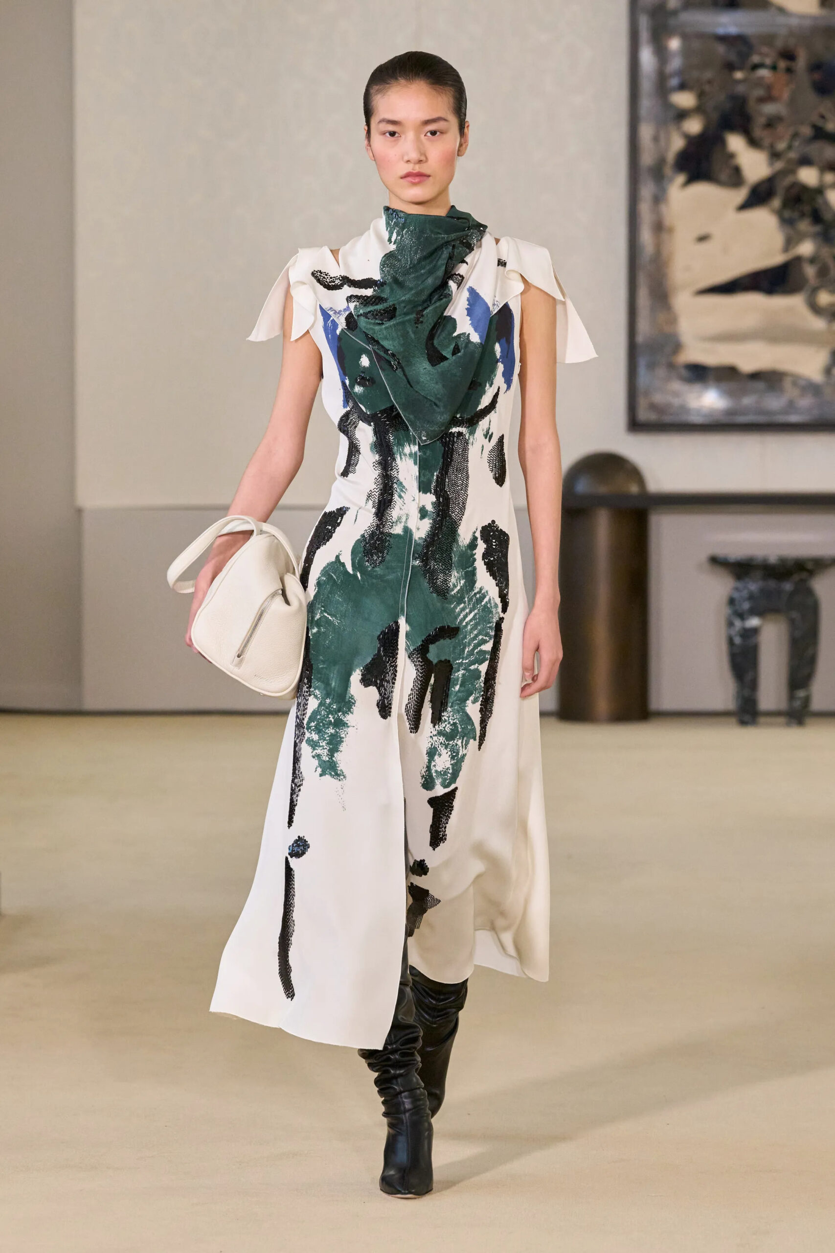 Model wearing a white abstract print dress with sequined detailing and black leather boots at Altuzarra Fall Winter 2026