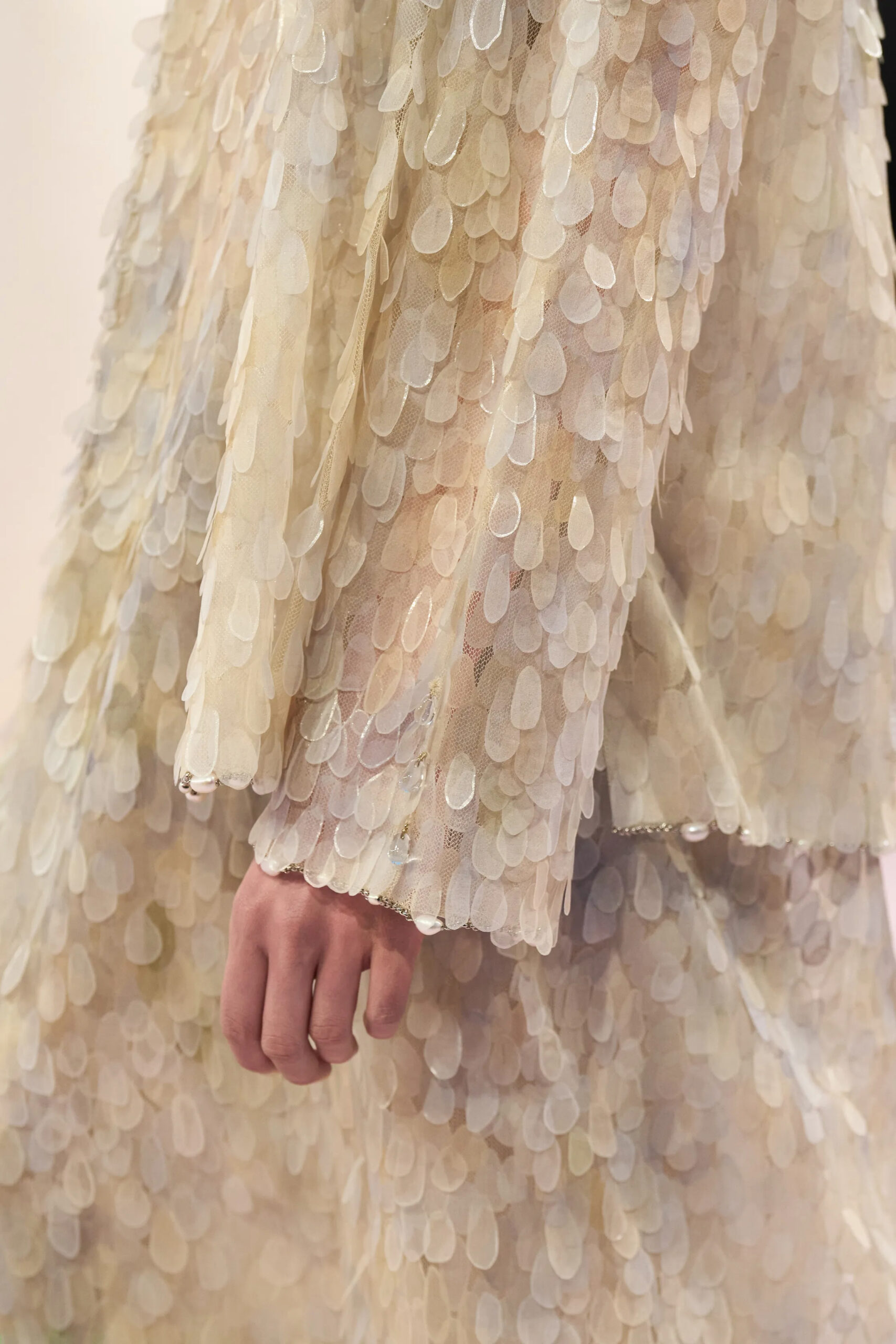 Close-up detail of ivory sequined Chanel couture fabric with layered translucent embellishment