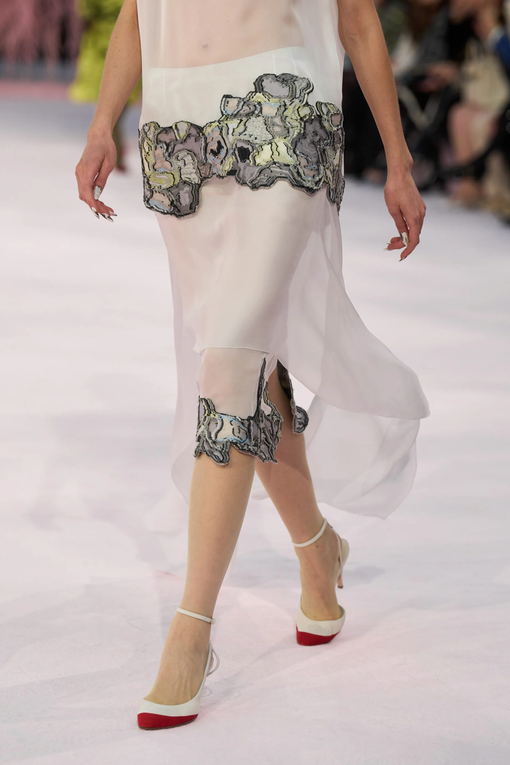 Close-up of sheer ivory Chanel couture dress with abstract embroidered detailing and white slingback heels