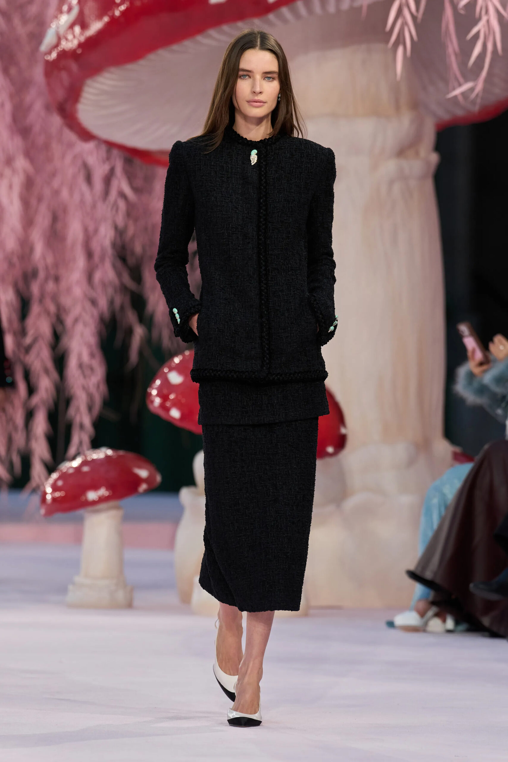 Model walking in a black Chanel tweed jacket and matching skirt with turquoise embellishments during Chanel Spring 2026 Couture