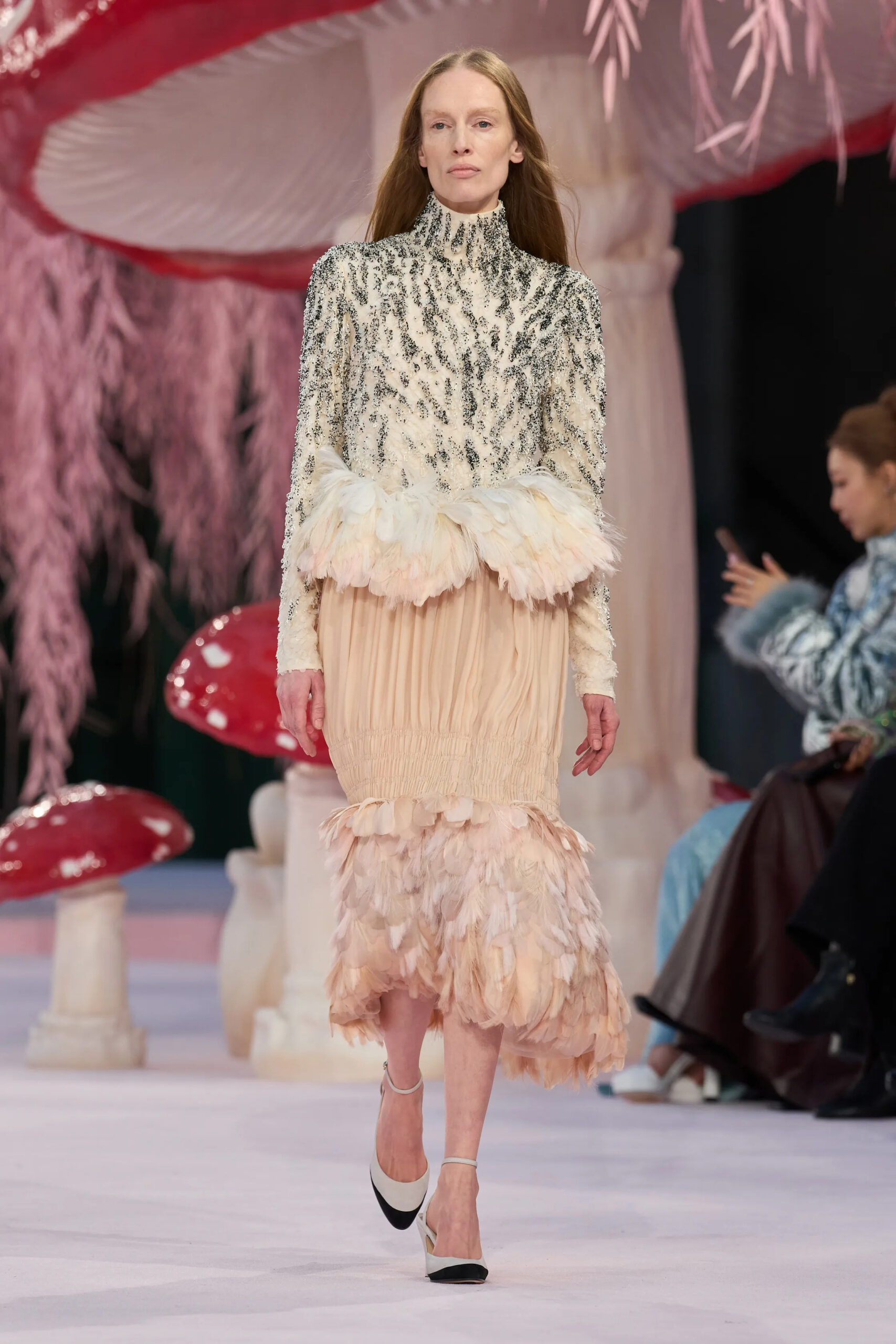 Model wearing a pale blush feathered Chanel couture dress with embellished bodice and gathered skirt on the runway