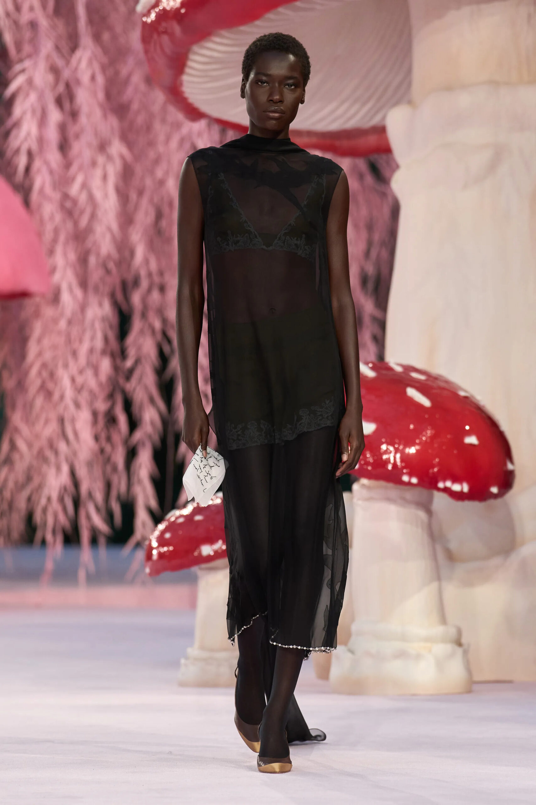 Model wearing a sheer black Chanel couture dress with transparent layered fabric and minimal styling