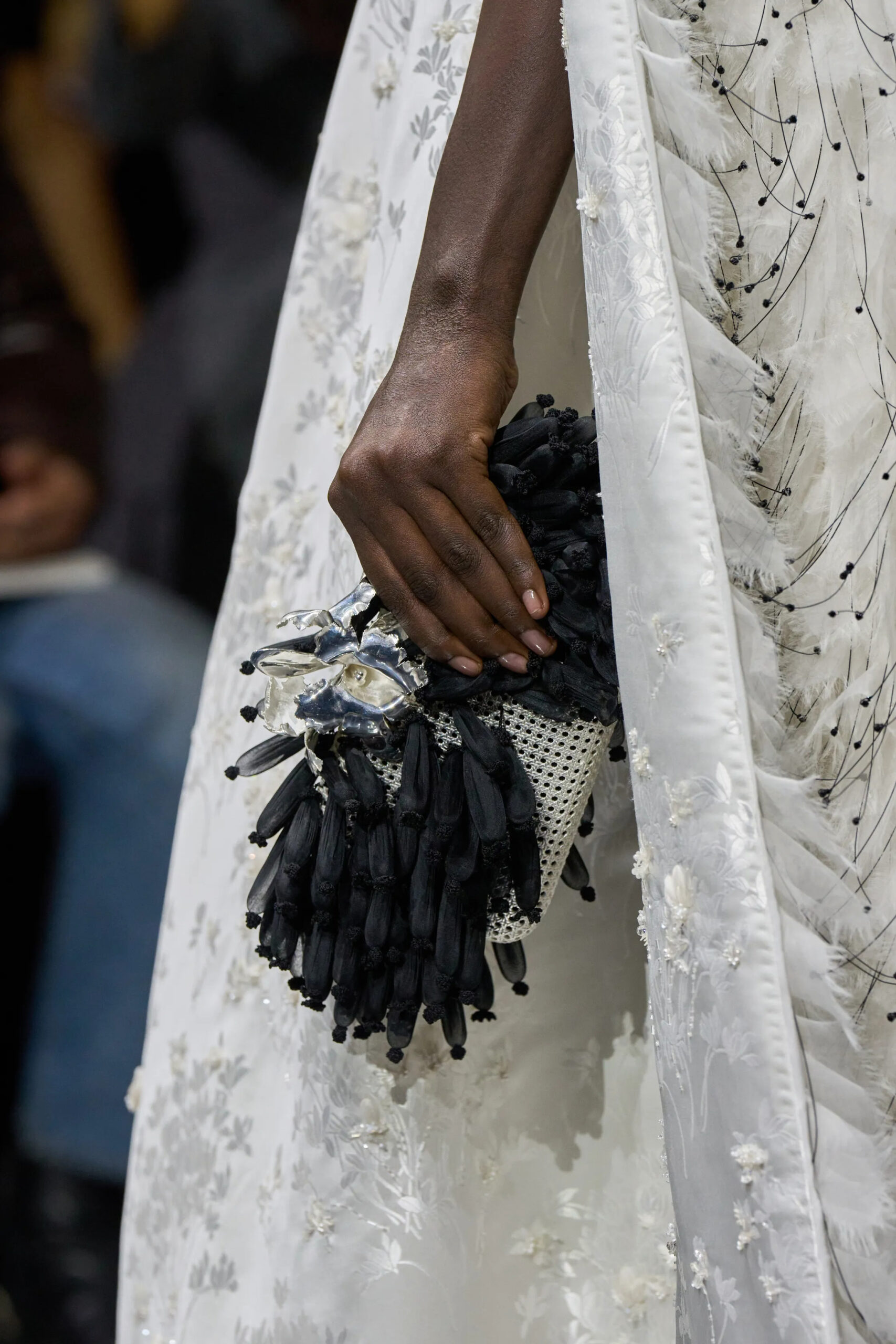 Close-up of black feathered Dior couture clutch with silver embellishment