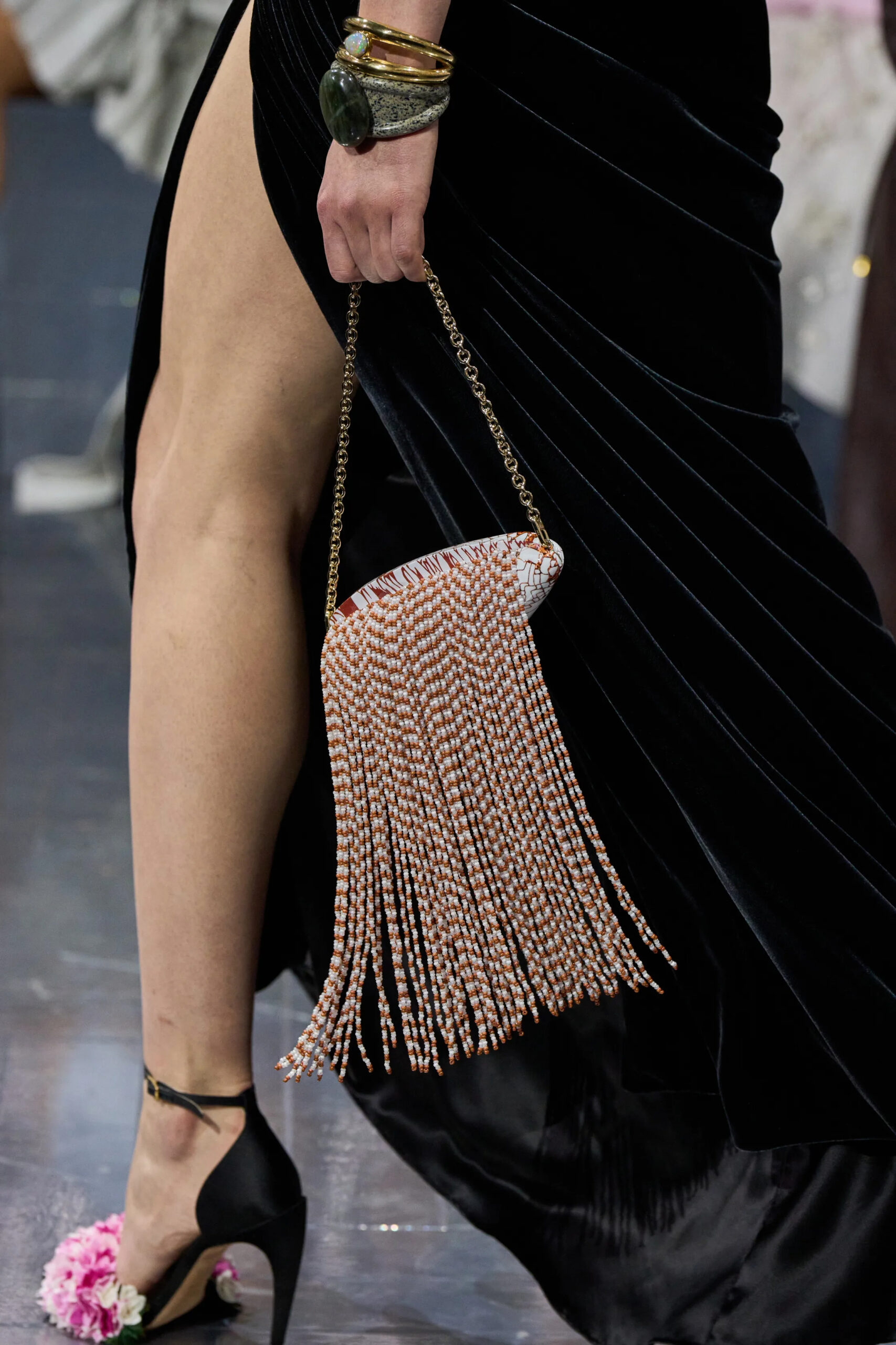 Close-up of Dior couture beaded fringe evening bag with black draped gown