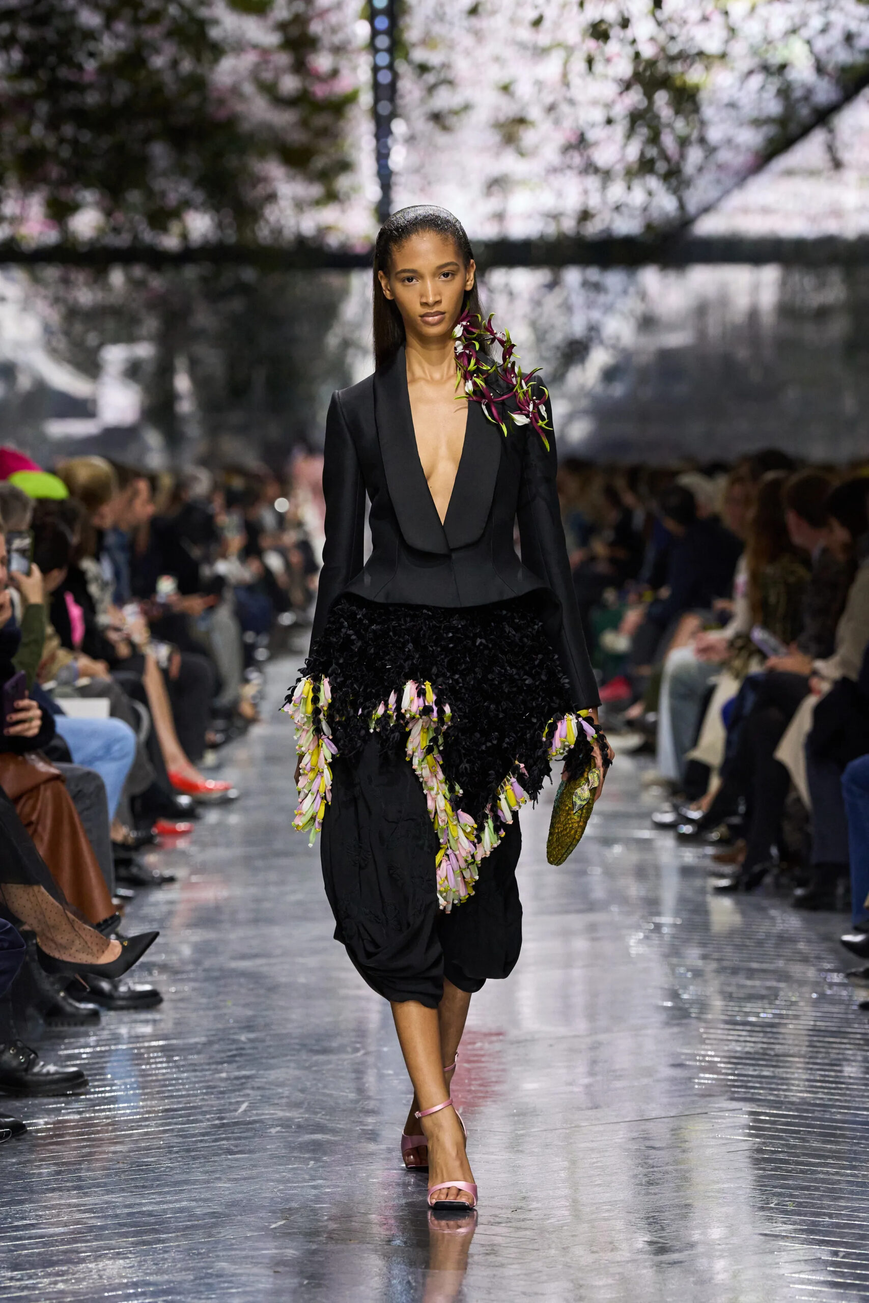 Model wearing black Dior couture tailored gown with plunging neckline and oversized floral shoulder details