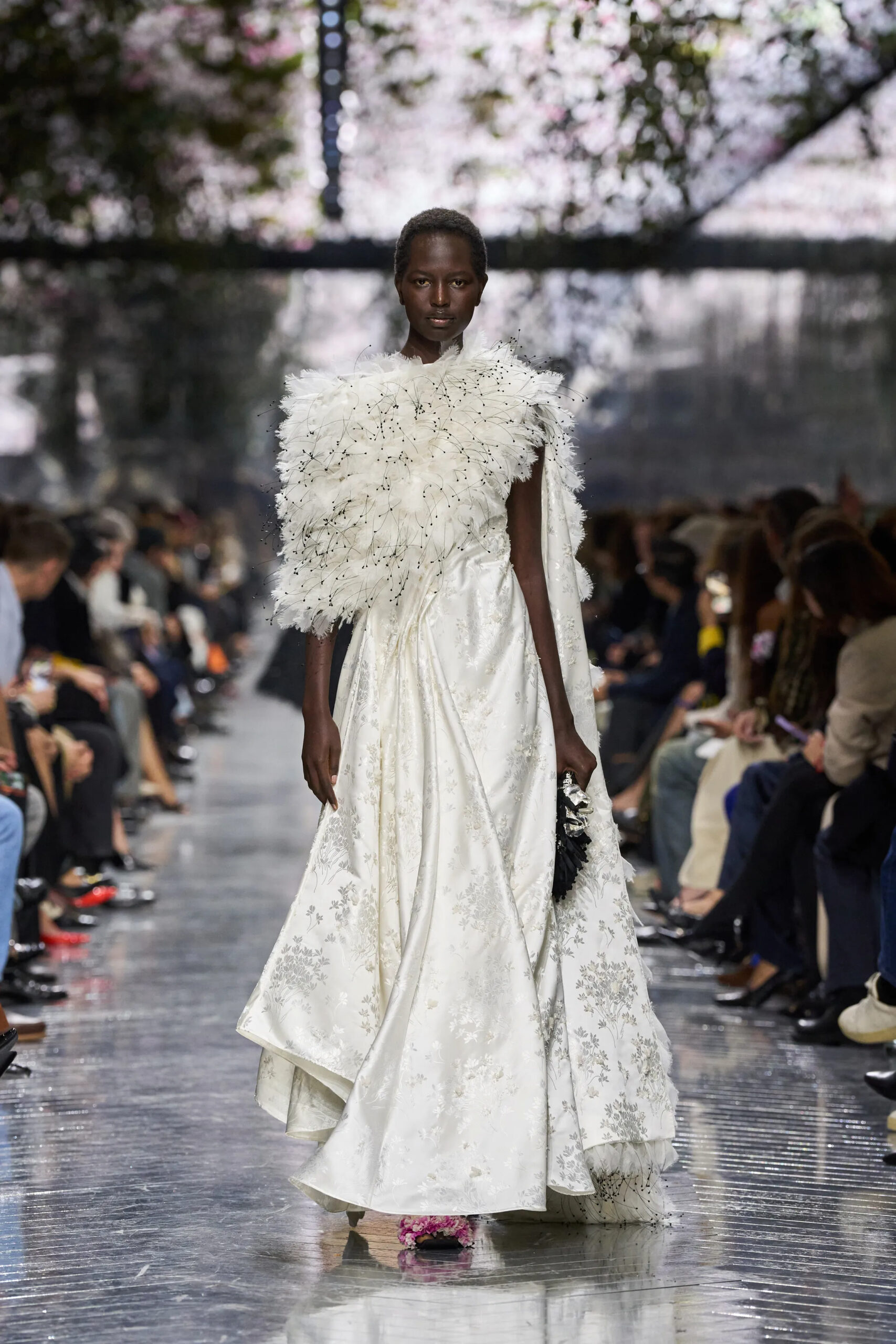 Model wearing white Dior couture gown with feathered bodice and embroidered floral fabric