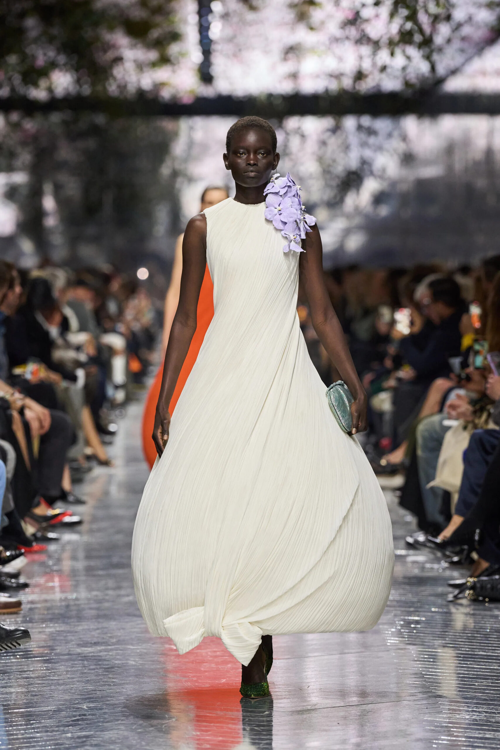 Model wearing flowing ivory Dior Spring 2026 Couture pleated gown with lavender orchid shoulder detail