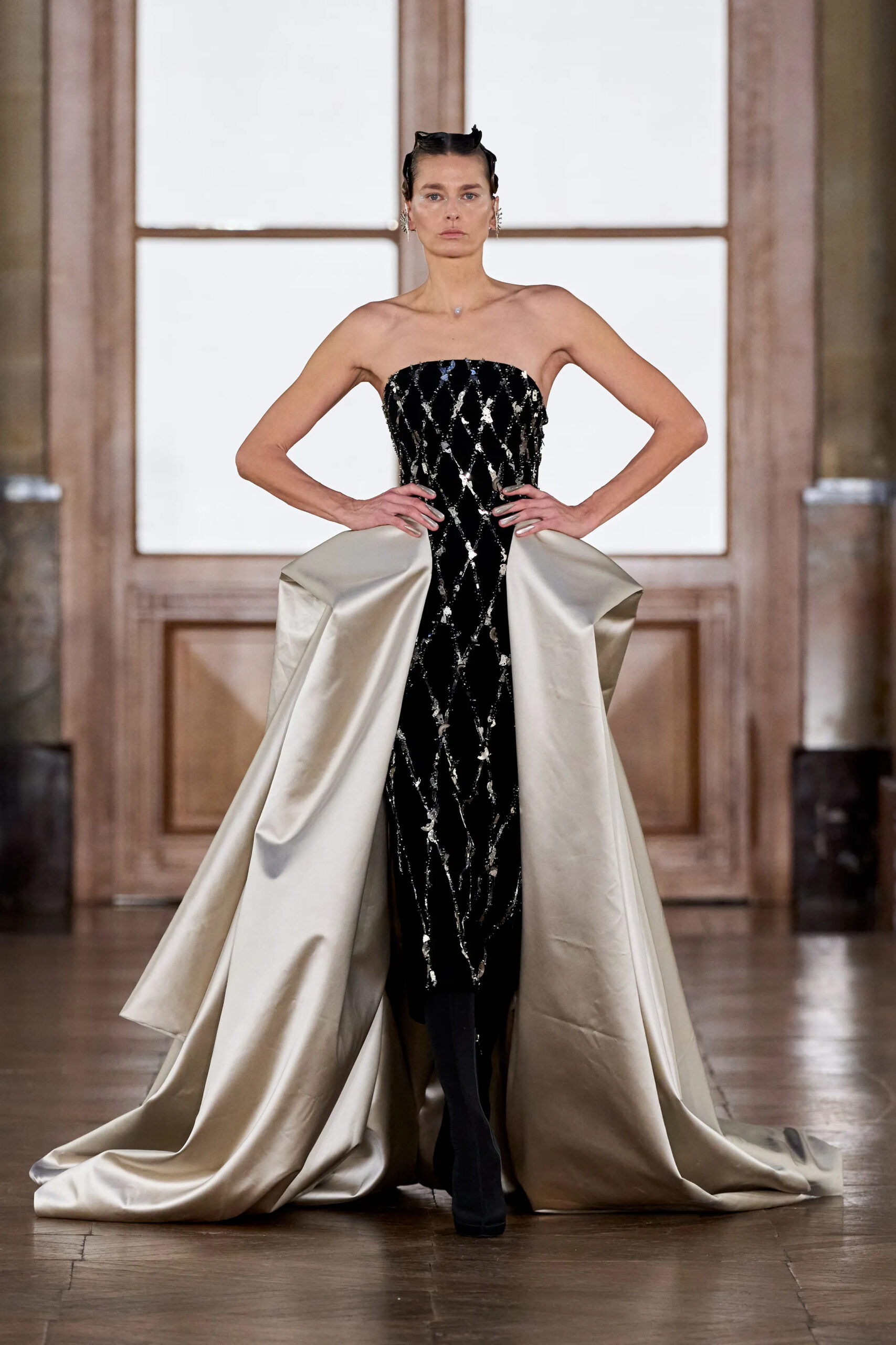 Model wearing a black embellished couture column gown with dramatic silver sculptural satin panels by Gaurav Gupta Spring 2026 Couture