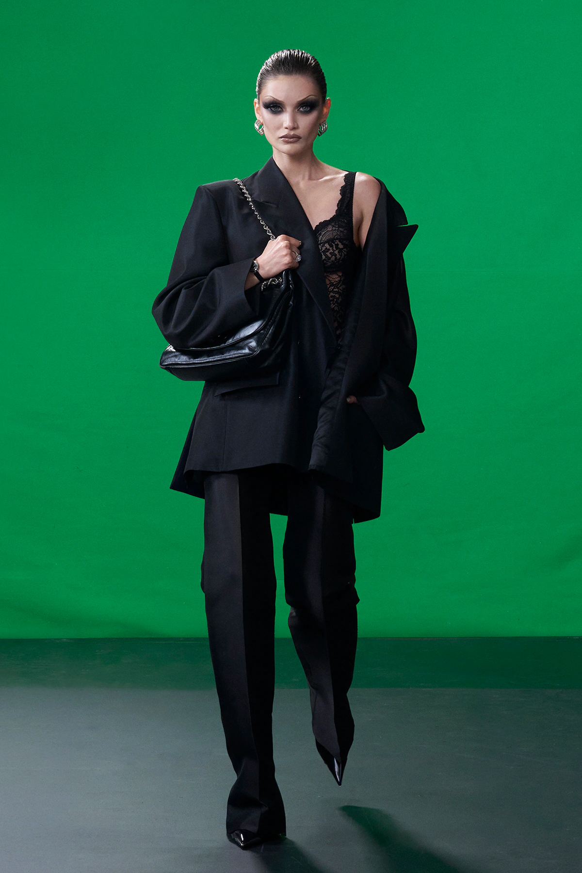 Model wearing oversized black Gucci tailoring with lace bodysuit and pointed boots during Gucci Resort 2027 in New York