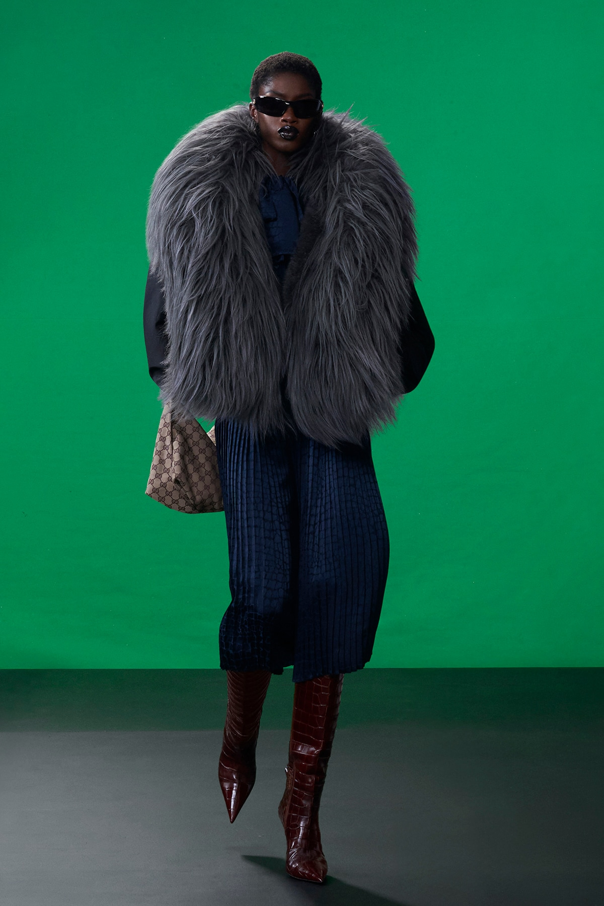 Model wearing oversized gray fur outerwear with crocodile boots during Gucci Resort 2027 in New York