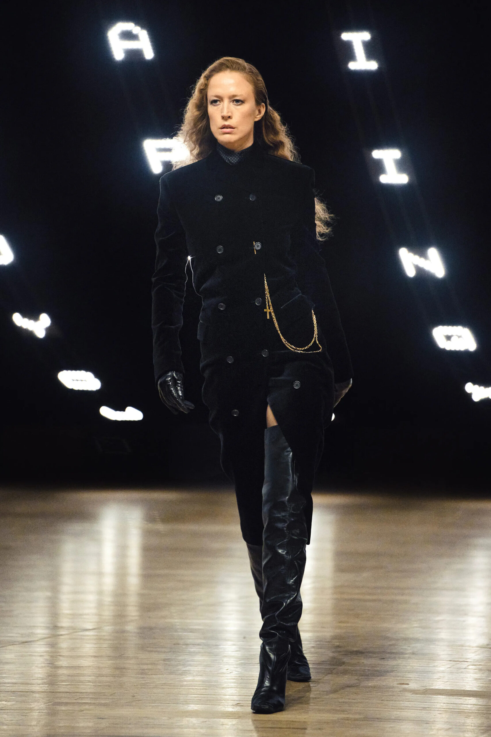 Model wearing a black velvet military-inspired coat dress with thigh-high leather boots at Khaite Fall Winter 2026 New York Fashion Week runway show