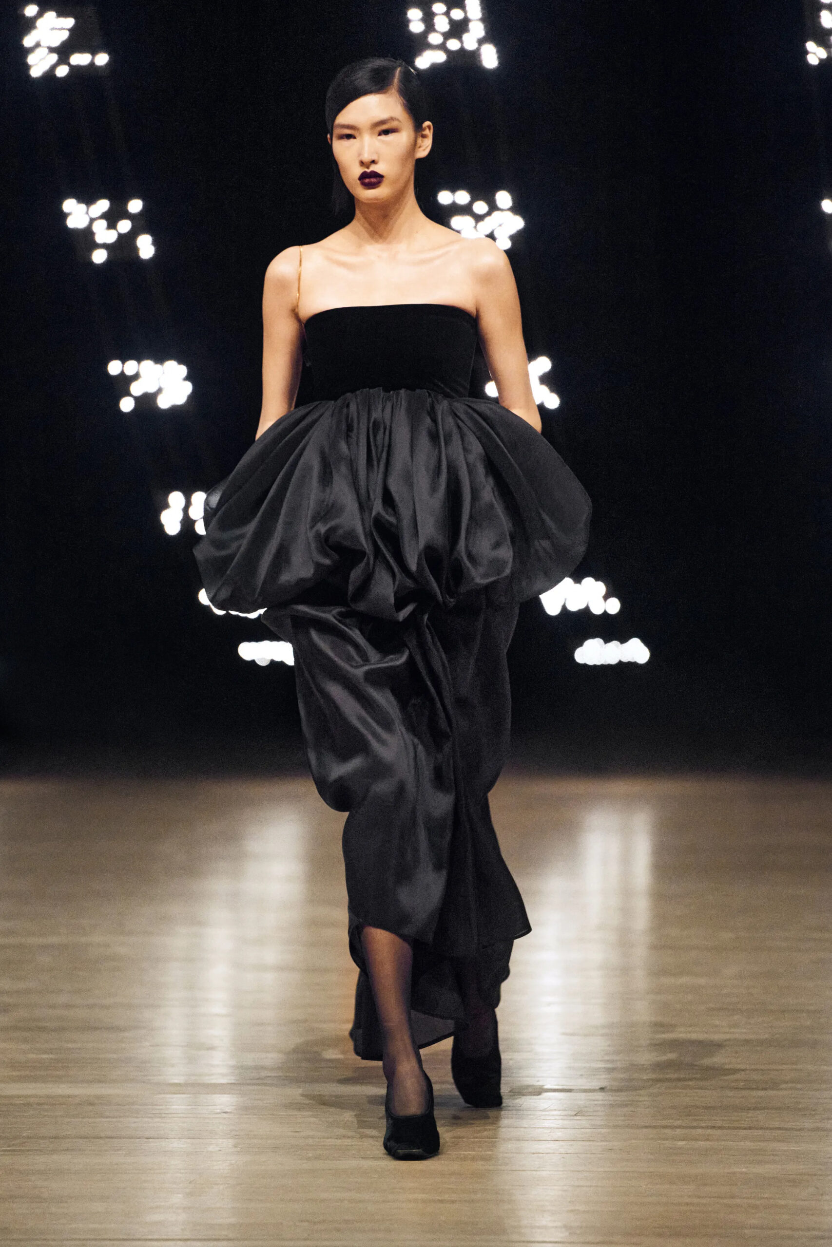 Model wearing a sculptural black dress with oversized gathered volume at Khaite Fall Winter 2026 runway show