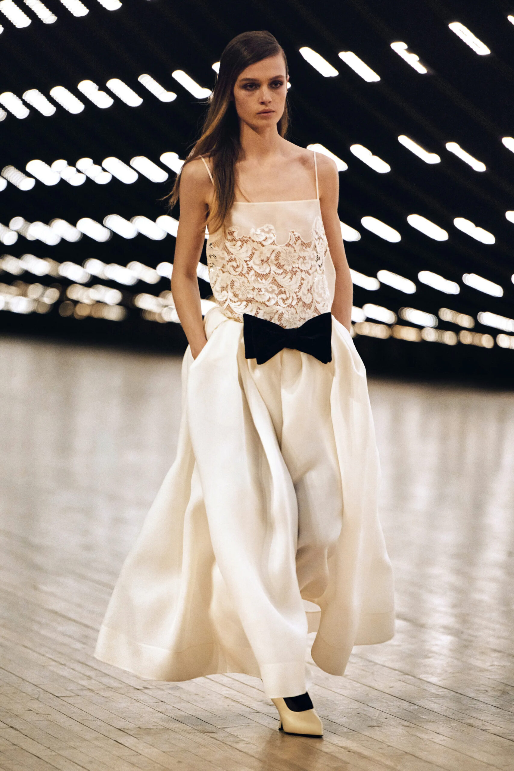 Model wearing an ivory lace top with oversized cream trousers and bow detail at Khaite Fall Winter 2026 runway show
