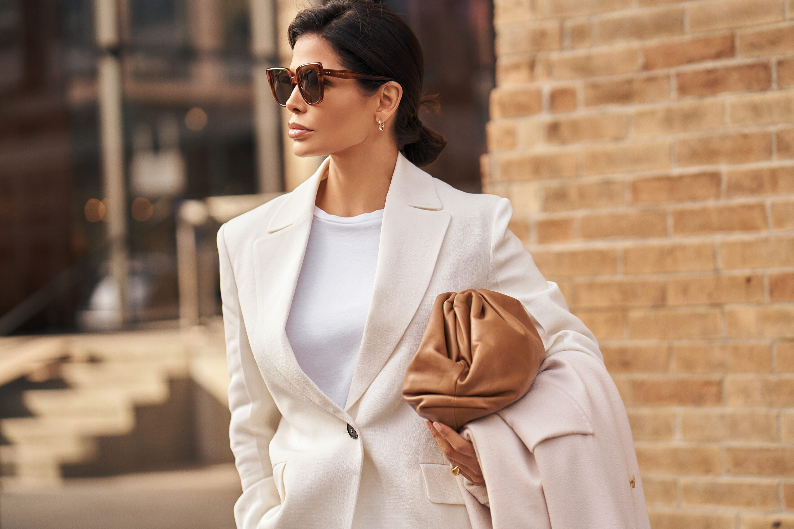 Side profile of Victoria Barbara wearing Jil Sander tailoring with a Max Mara coat and Bottega Veneta clutch on a New York street.