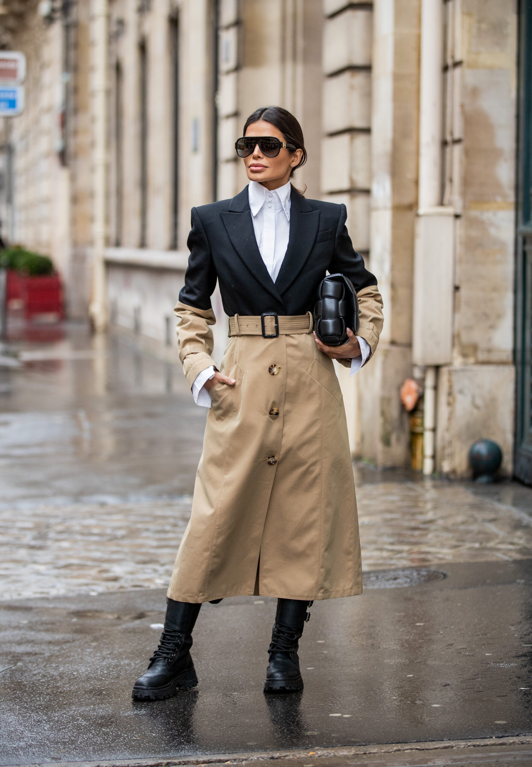 Full-length street style portrait of Victoria Barbara in a structured two-tone trench coat with combat boots and oversized sunglasses during Paris Fashion Week.