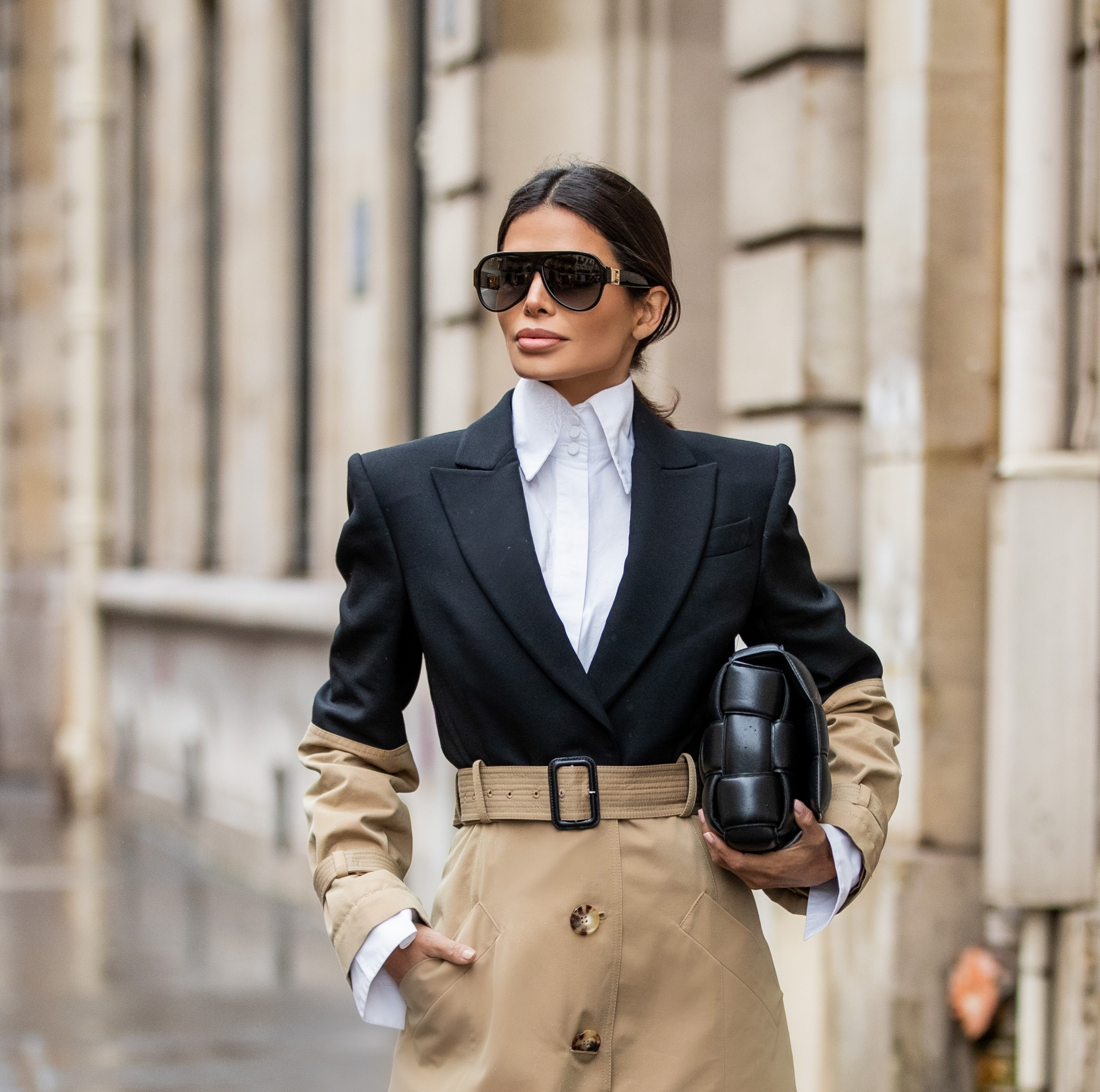 Close-up portrait of Victoria Barbara wearing a structured trench coat, white shirt, oversized sunglasses, and sleek low ponytail in Paris.