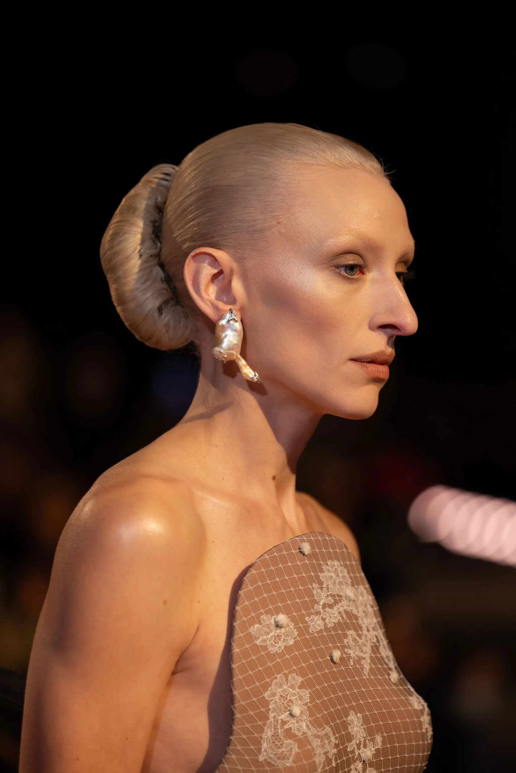 Close-up portrait featuring pearl Schiaparelli couture earrings and sleek hair styling