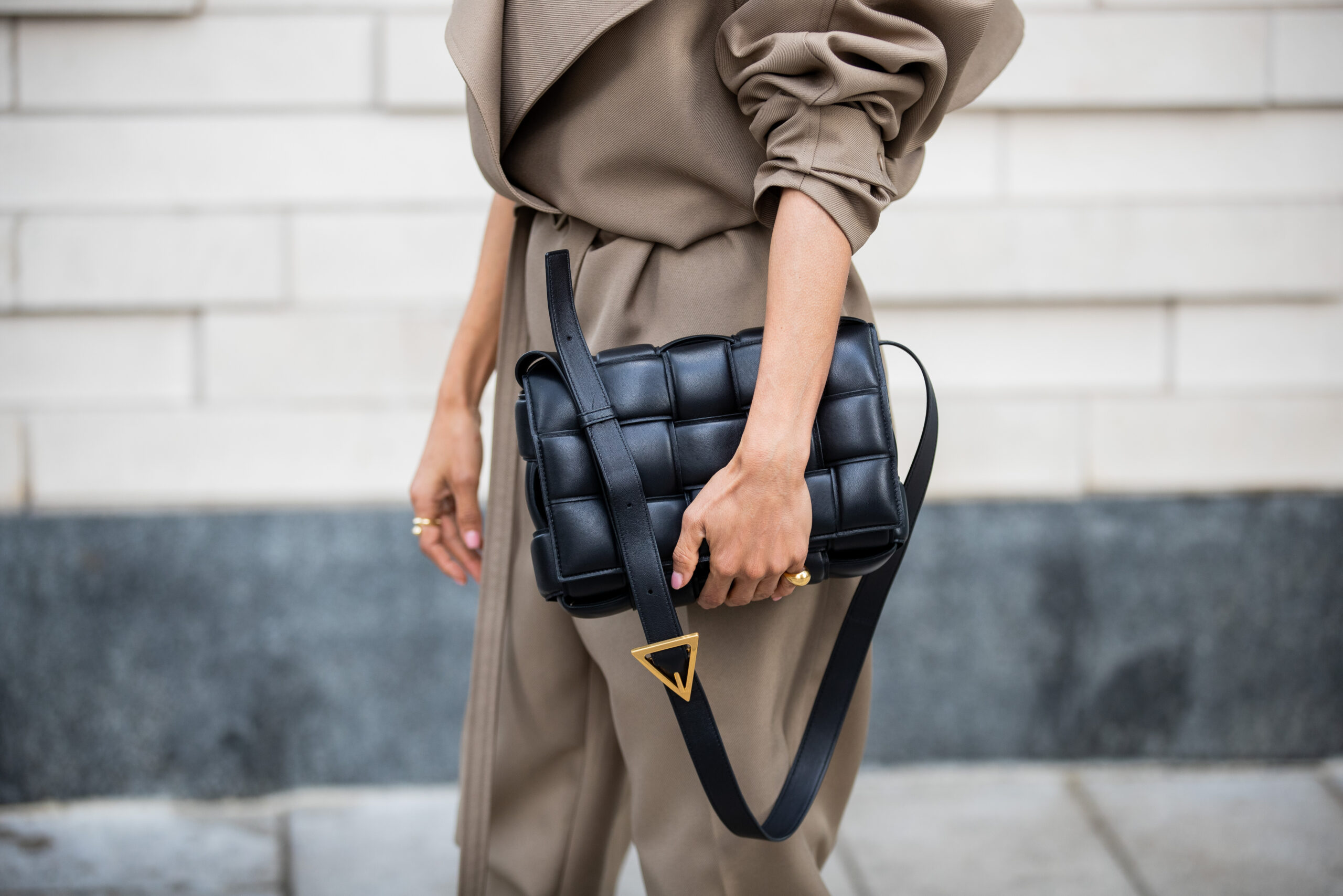 Detail image of a black woven Bottega Veneta bag carried with a Bottega Veneta utility jumpsuit.
