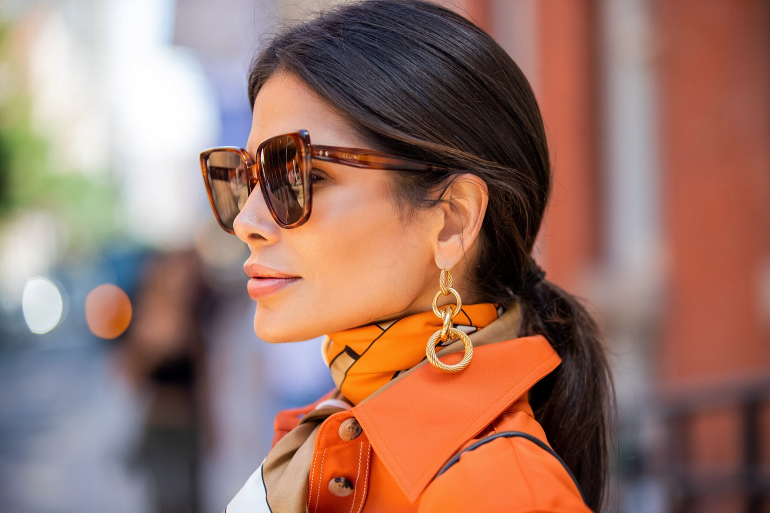 Close-up of Victoria Barbara wearing CELINE sunglasses, a Burberry scarf, and Bottega Veneta earrings.