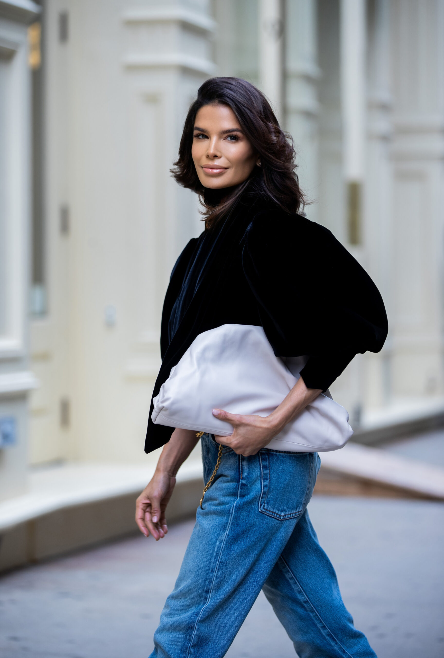 Victoria Barbara carrying a Bottega Veneta clutch while wearing a black KHAITE velvet top and Balenciaga denim during New York Fashion Week.