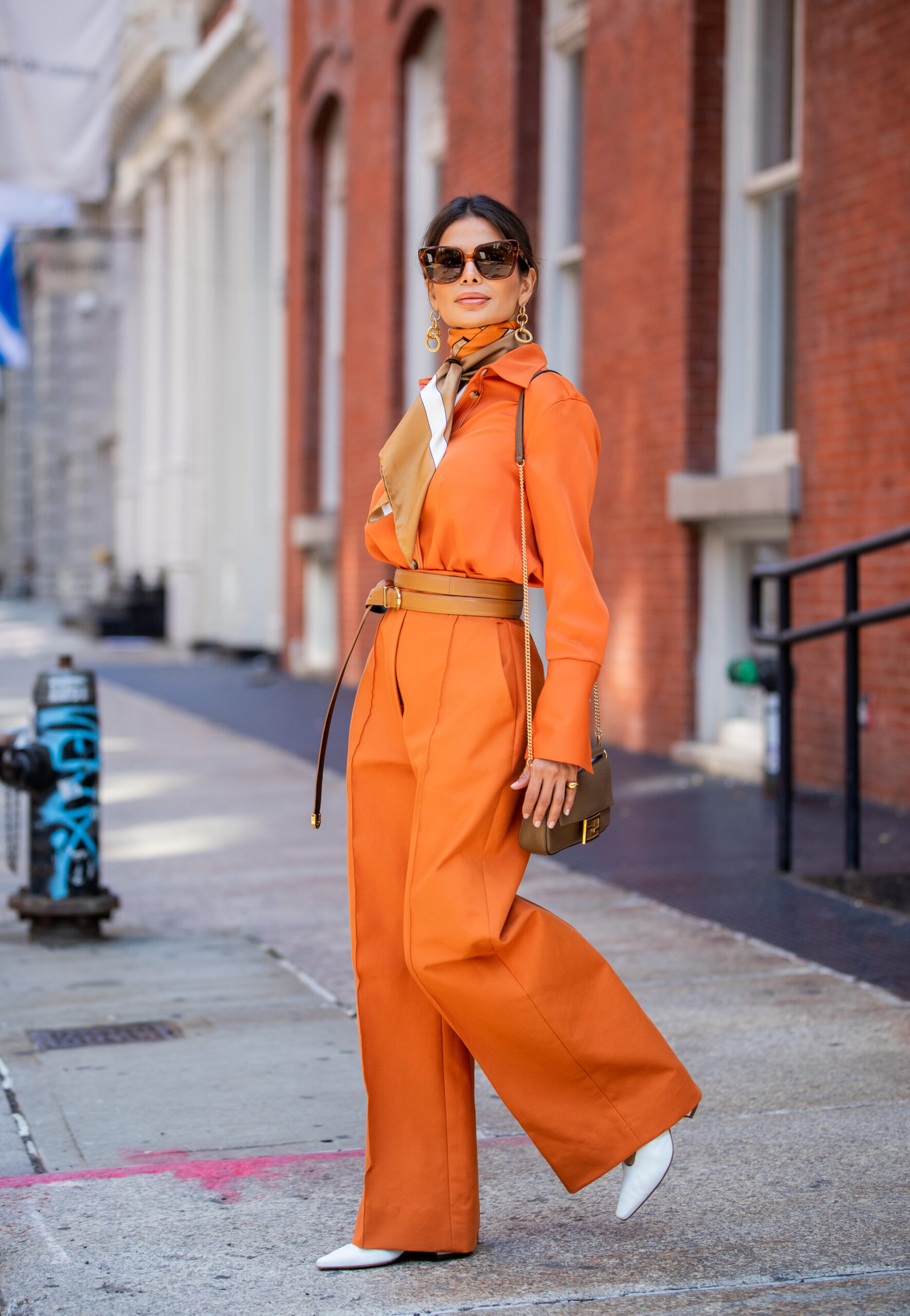 Victoria Barbara walking in New York City wearing a KHAITE shirt and trousers styled with a Burberry scarf and Bottega Veneta shoes.